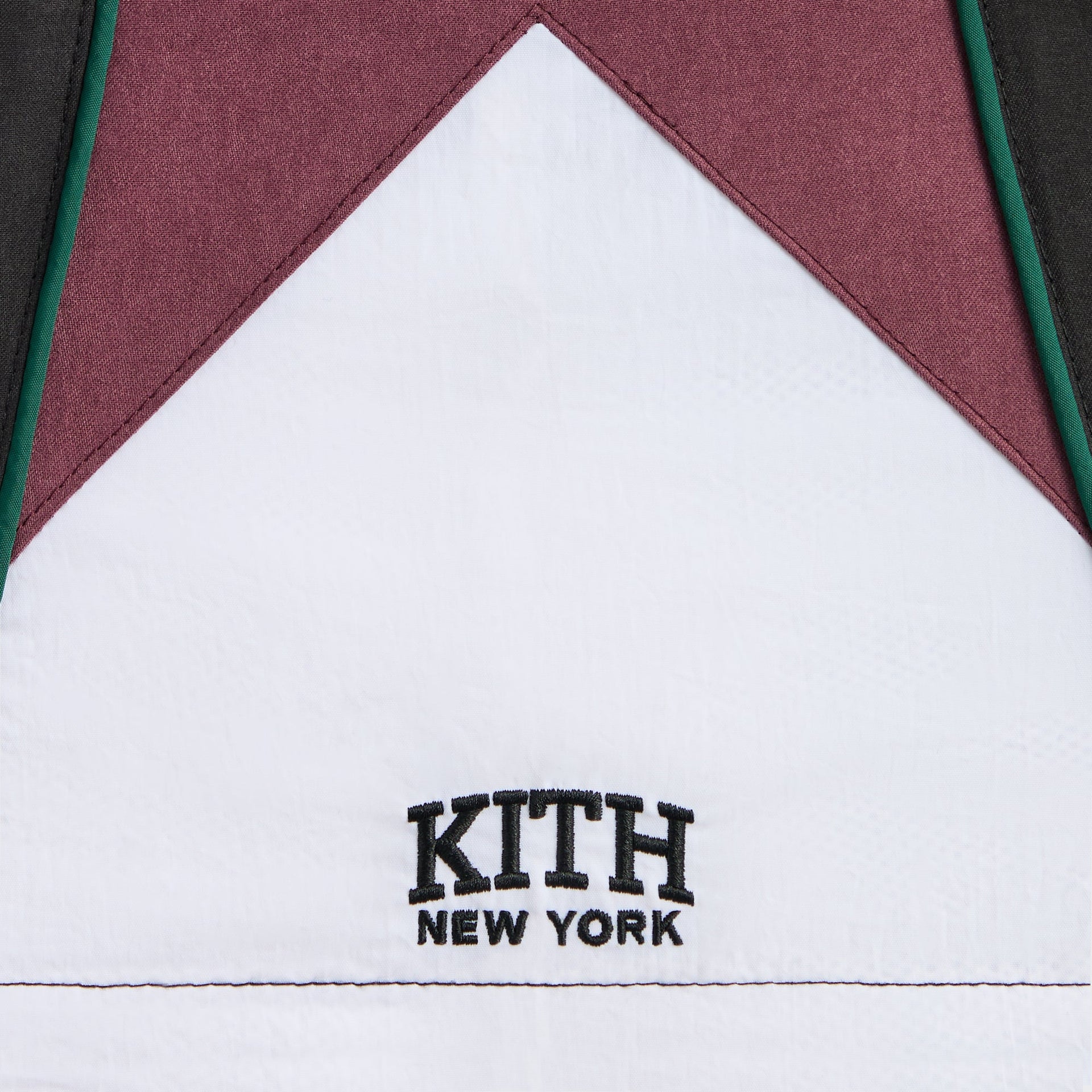 Kith Kids Blocked Track Skirt in Black, close-up of white panel with black KITH New York logo and green piping