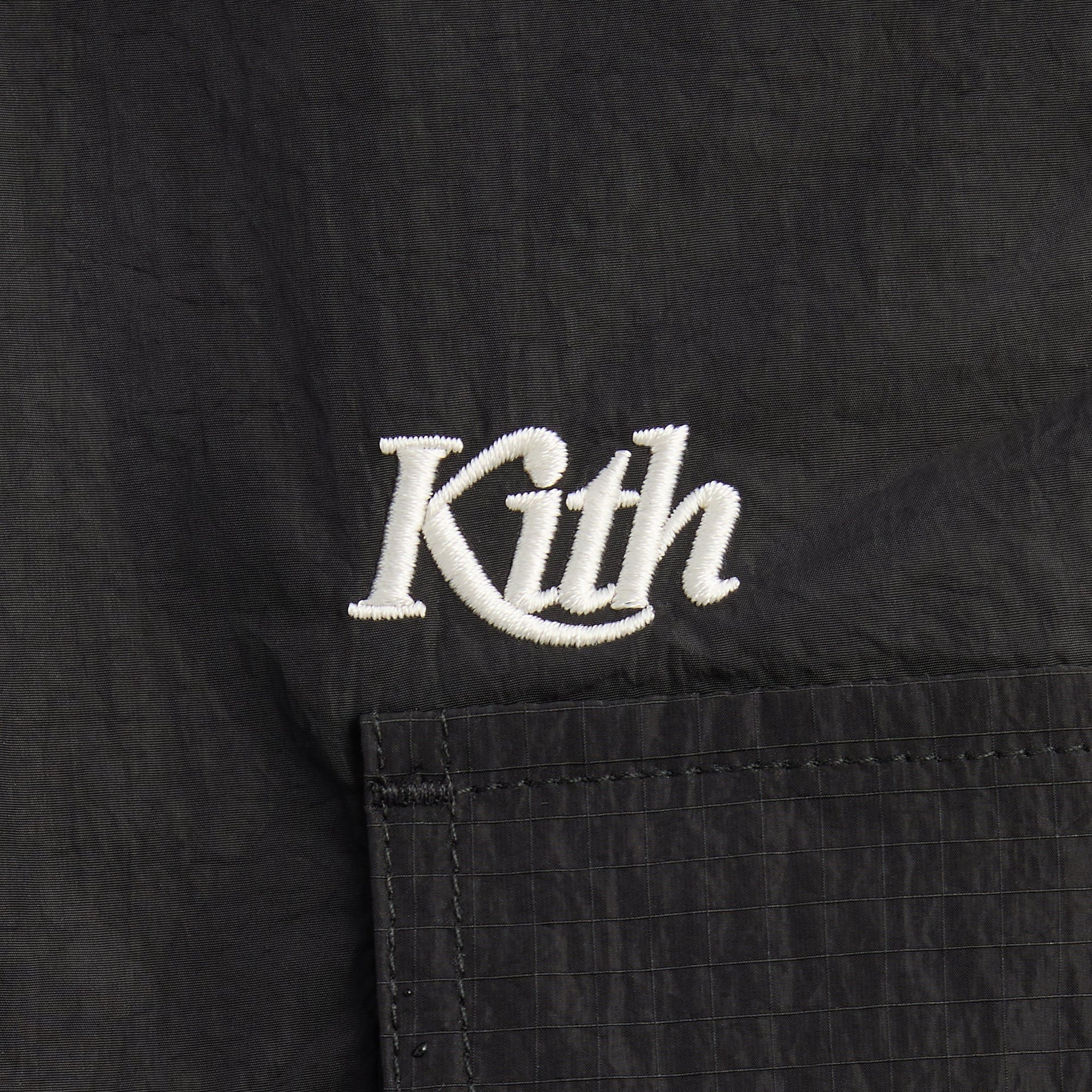 Kith Kids Kaiden Pant in Black, close-up of white Kith script embroidery above ripstop cargo pocket