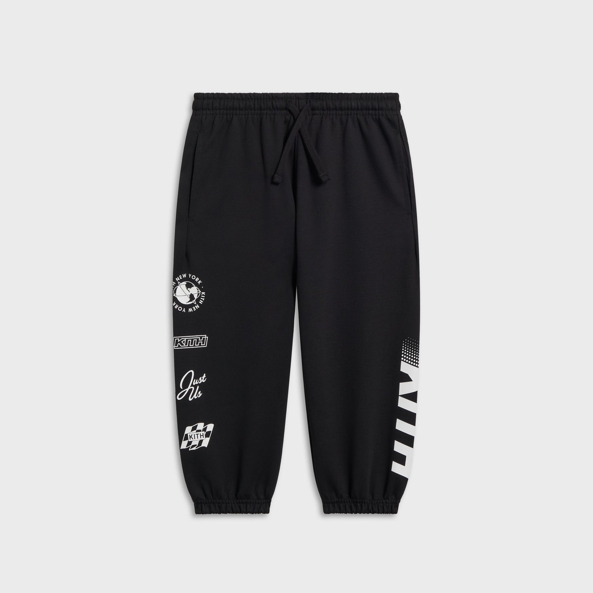 Kith Kids Logo Blocked Nelson sweatpant in black, flat lay with multiple KITH logo graphics down the leg including a globe emblem and checkered flag