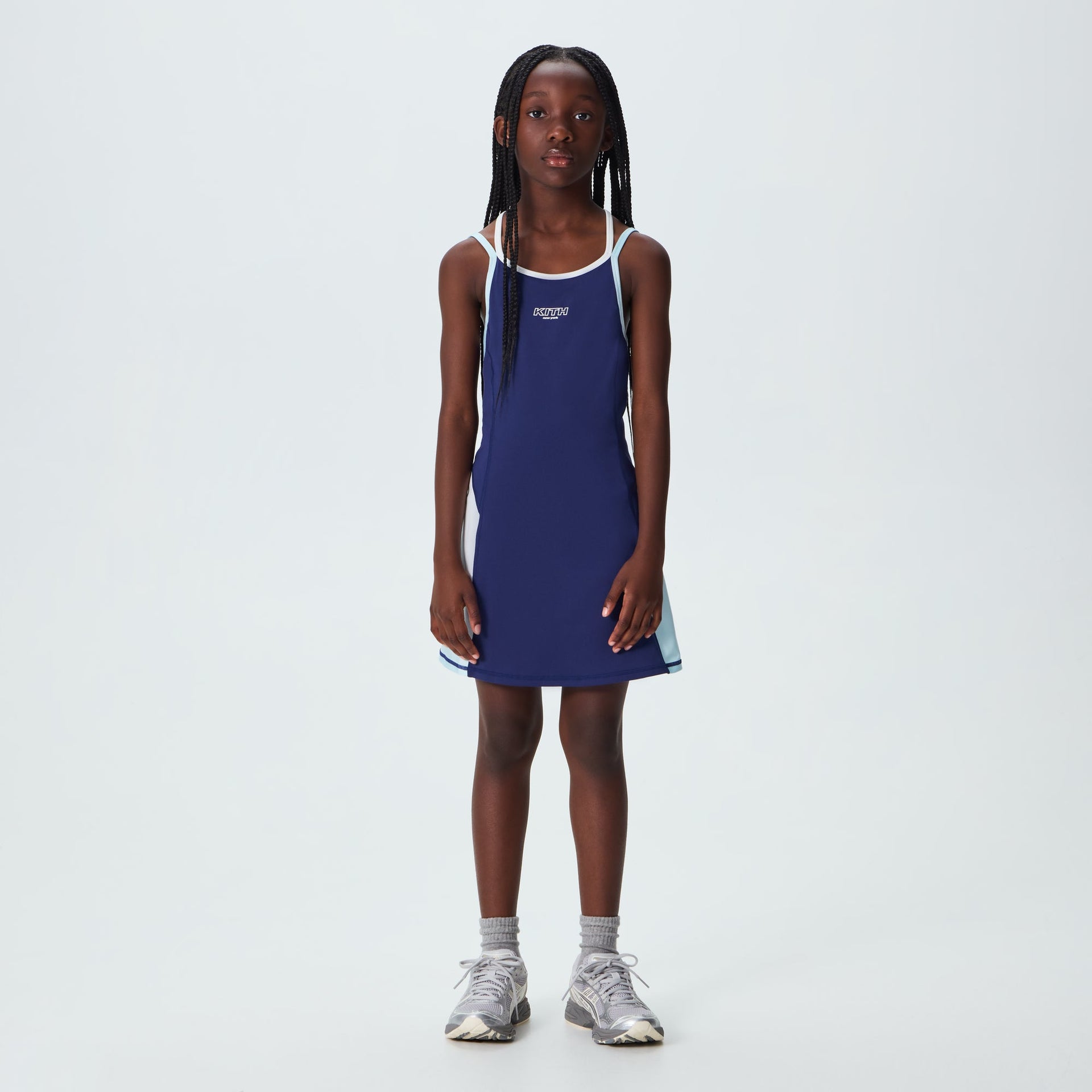 Kith Kids Active Skye Romper Dress in Nocturnal navy worn by young girl, front on-model view with sneakers