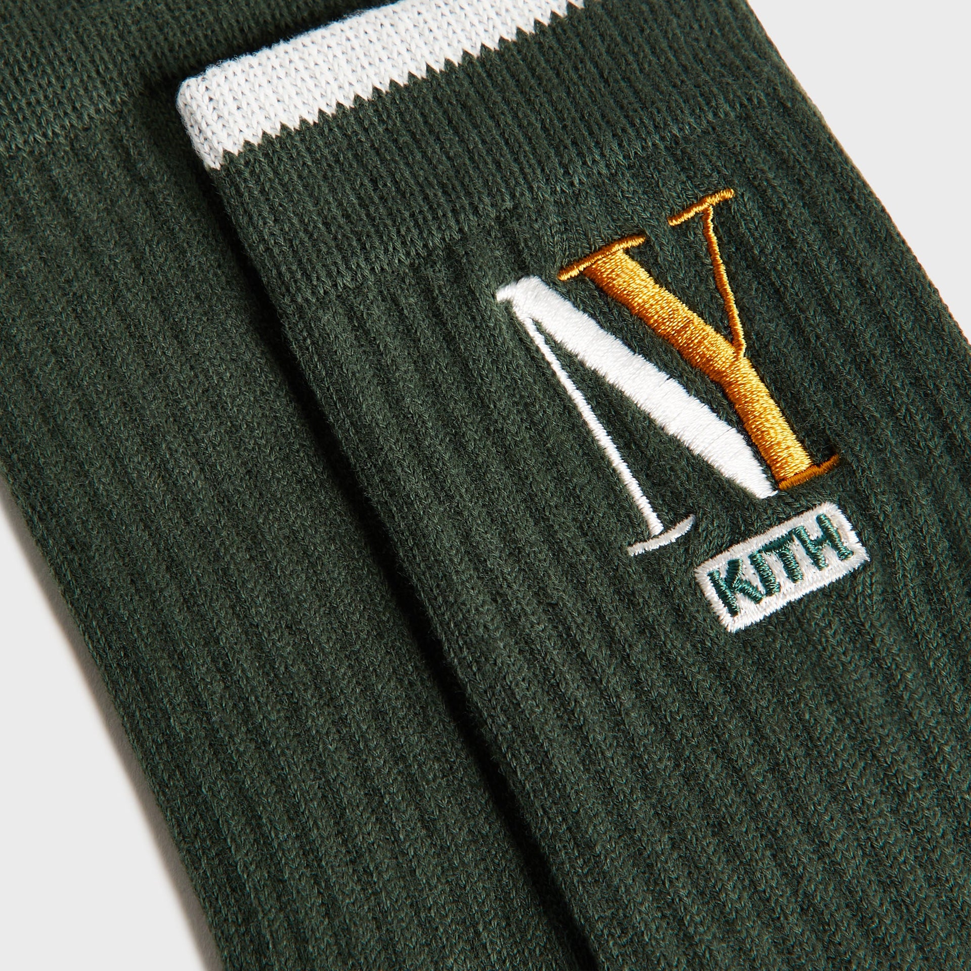 Kith Kids NY Socks, close-up of green sock with white stripe and gold NY Kith embroidery