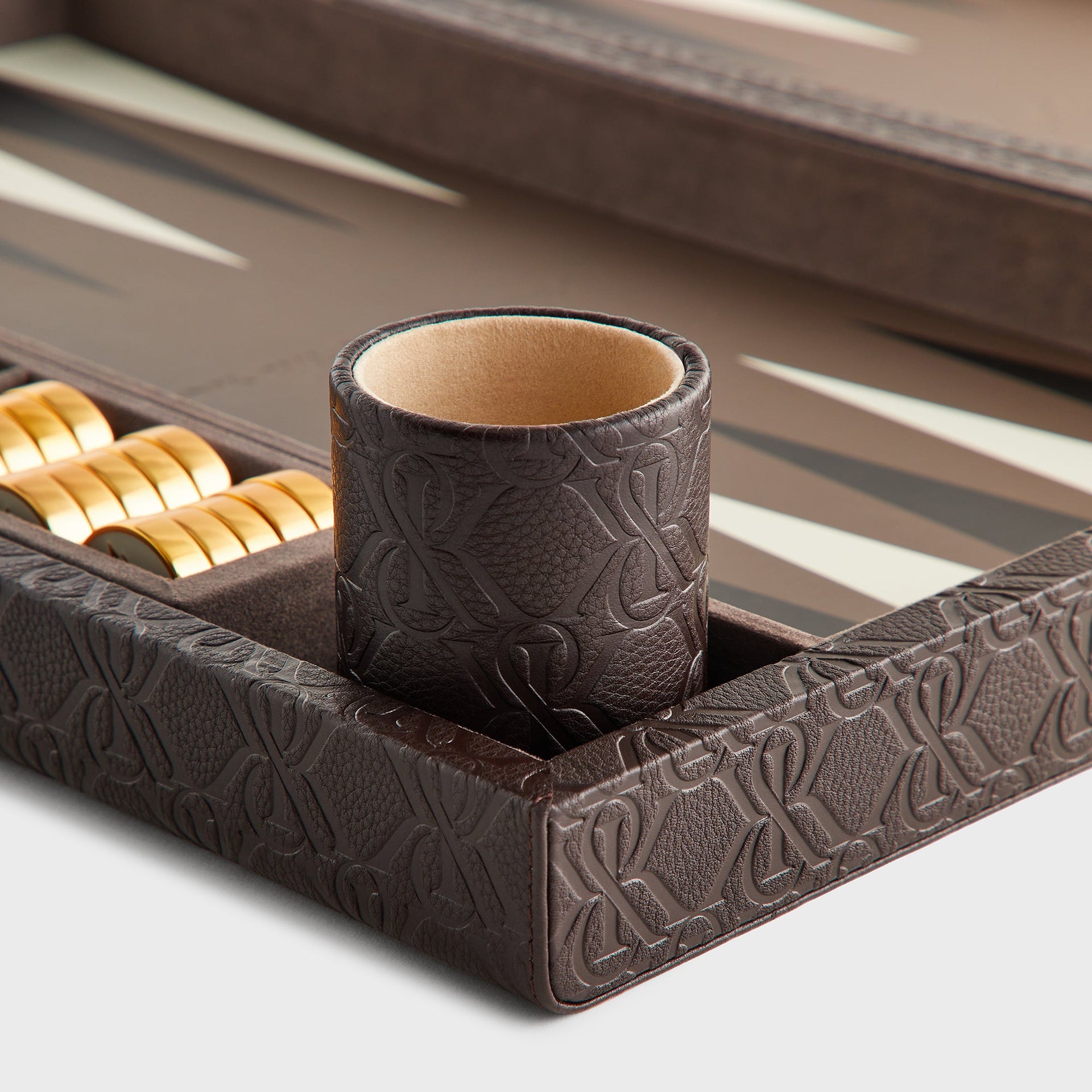 Close-up of the embossed leather dice cup with suede interior set in the backgammon board's corner tray