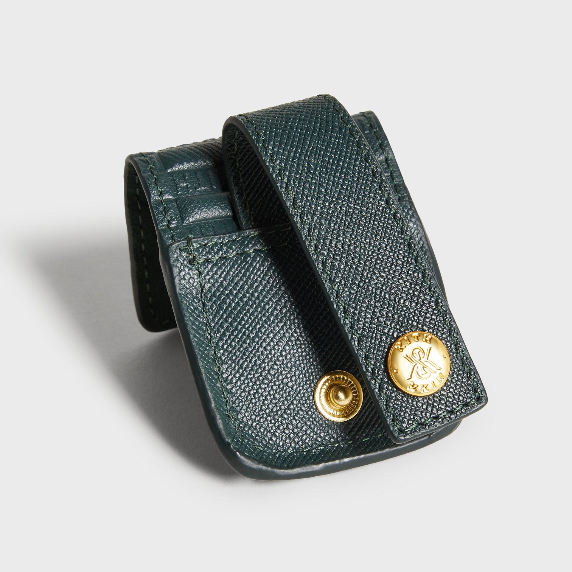 Kith Monogram Lighter Case in Stadium, close-up of gold snap buttons with engraved Kith & Kin logo on strap