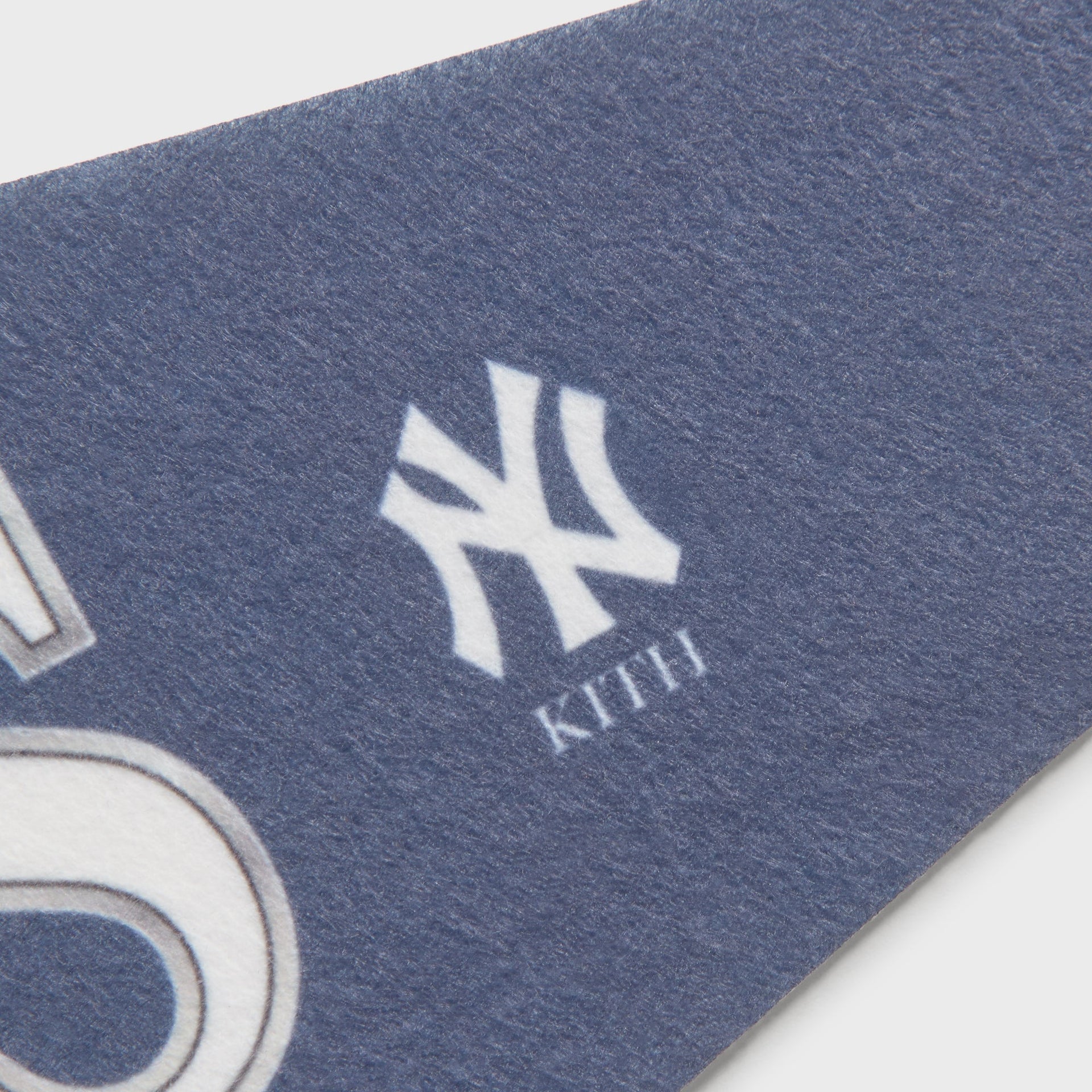 Close-up of the small NY and Kith logo printed near the tip of the navy pennant flag