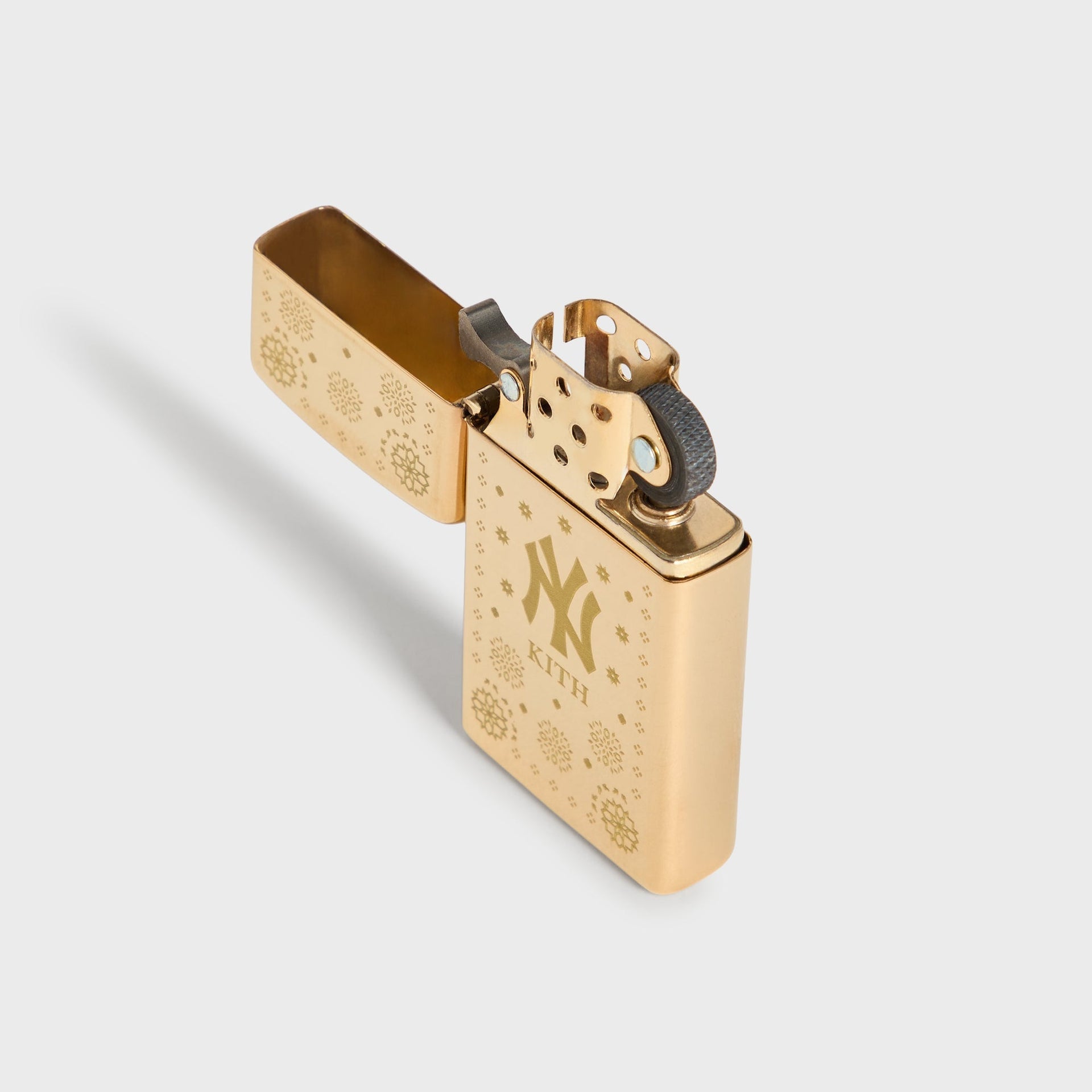 Kith x New York Yankees gold Zippo lighter open at an angle, showing hinge and flint wheel