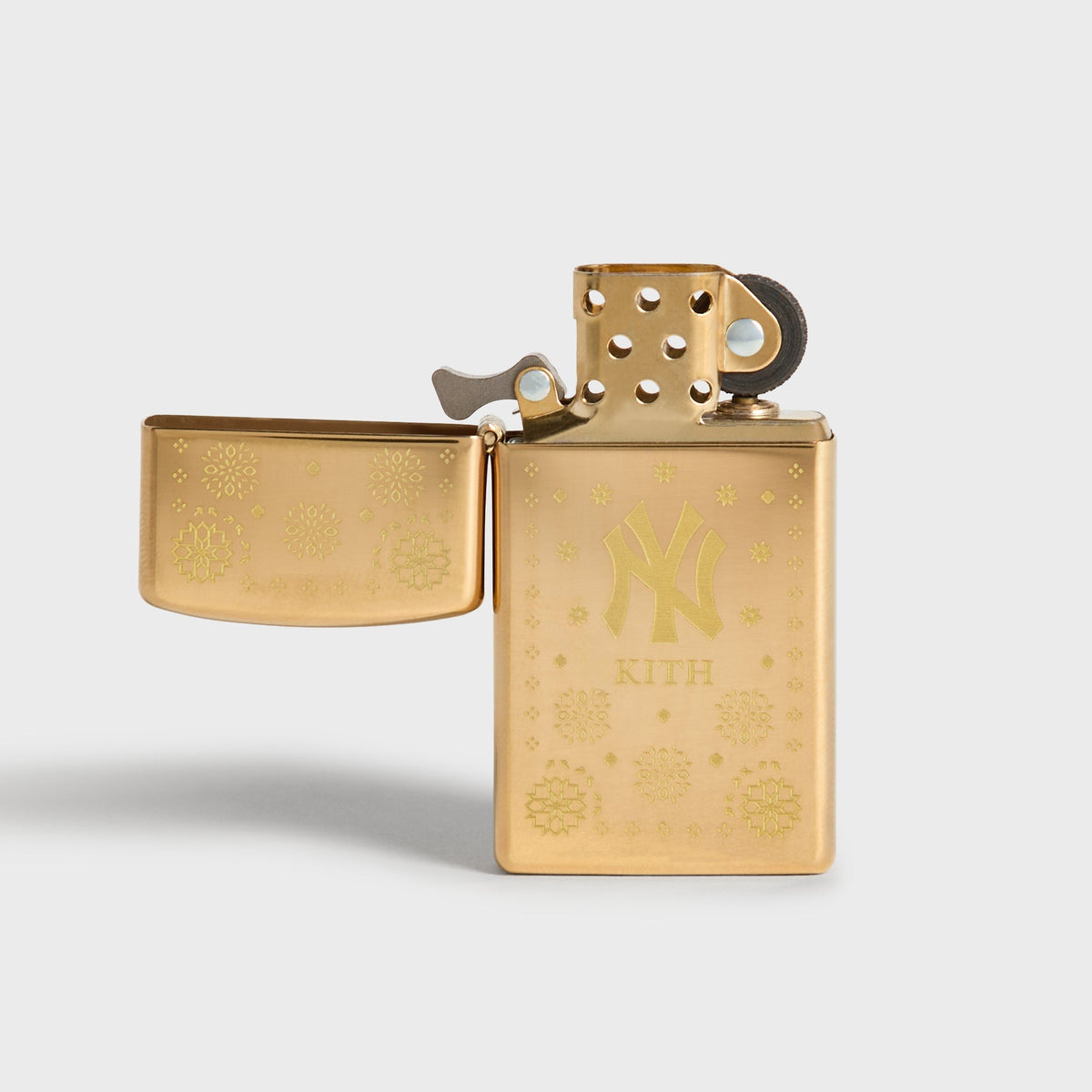 Kith x New York Yankees gold Zippo lighter open, showing flint wheel and NY logo front