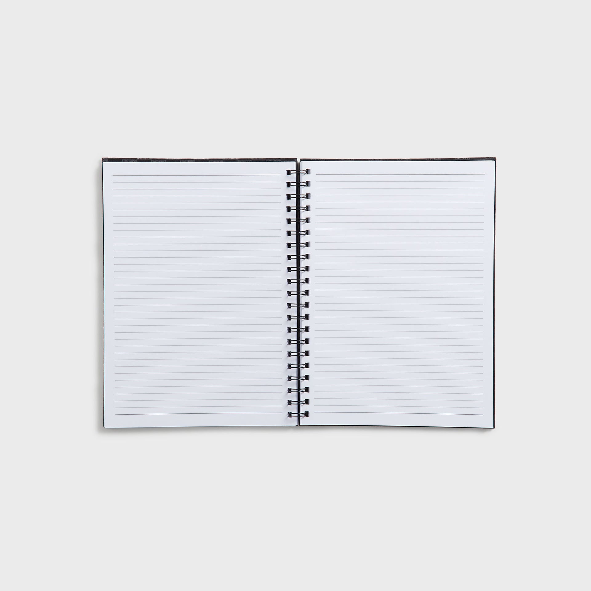 Open Kith Kids spiral notebook showing blank white lined pages and black wire binding