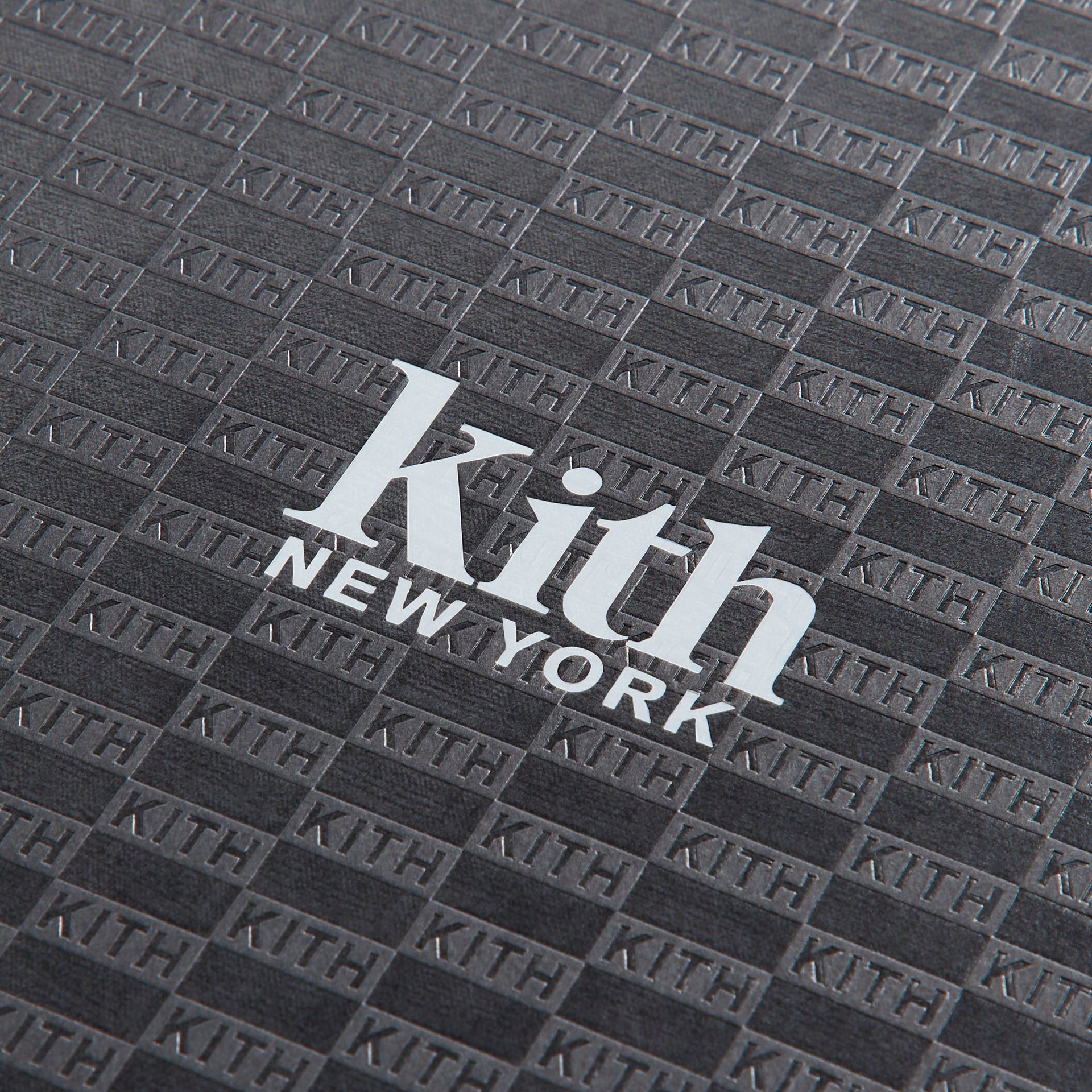 Close-up of embossed tonal KITH monogram pattern and silver Kith New York logo on black cover