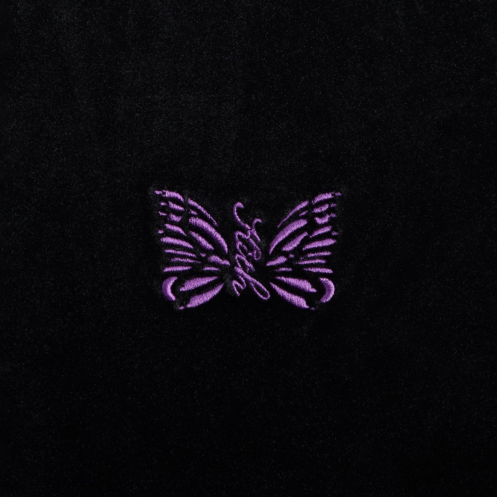 Close-up of the purple embroidered butterfly logo on the Kith for Needles Rui track jacket chest