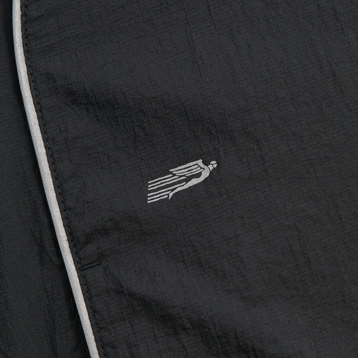 Close-up of Kith Eryx Track Jacket chest wing logo embroidered in reflective grey