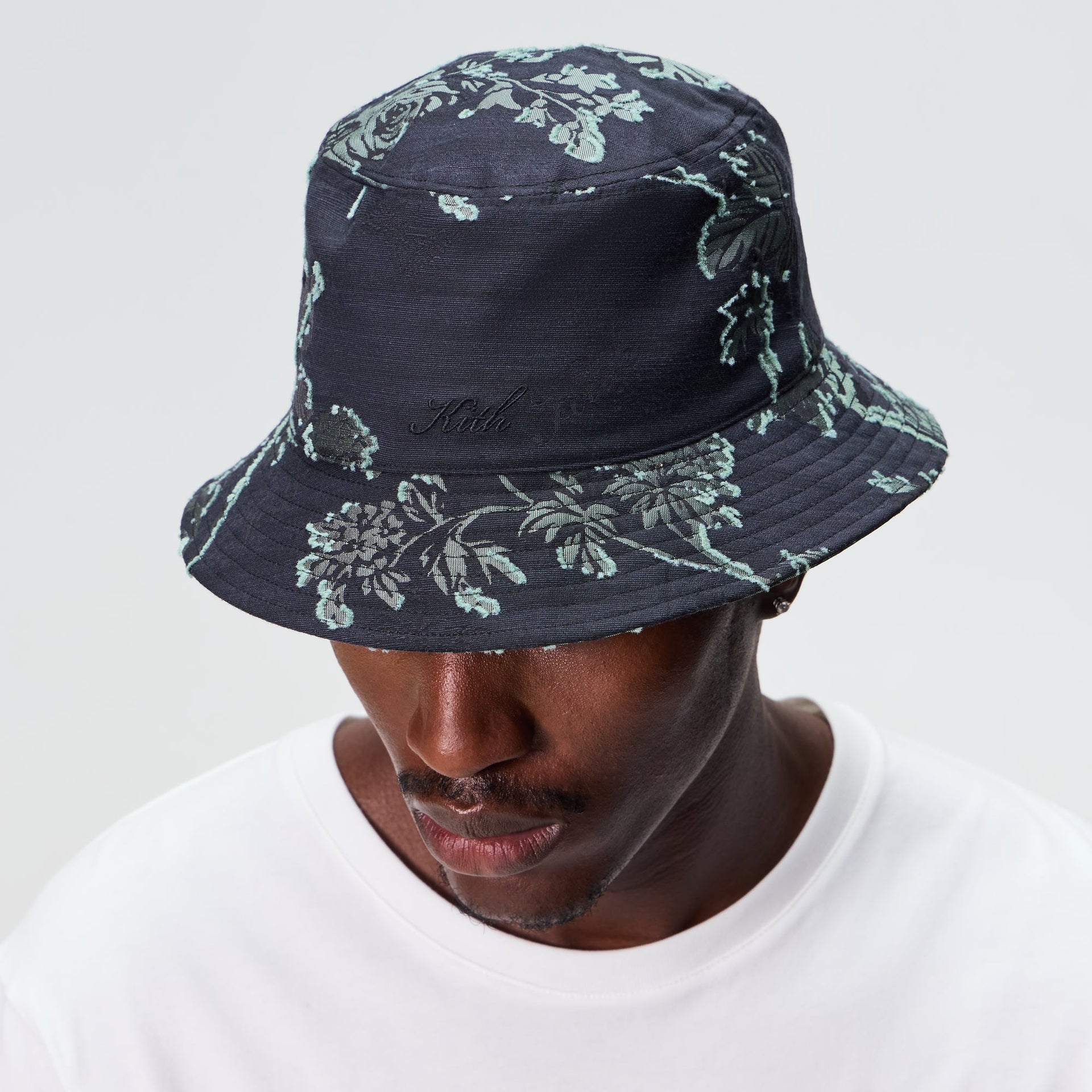 Man wearing the Kith for Needles Dawson bucket hat in black floral jacquard with a white t-shirt