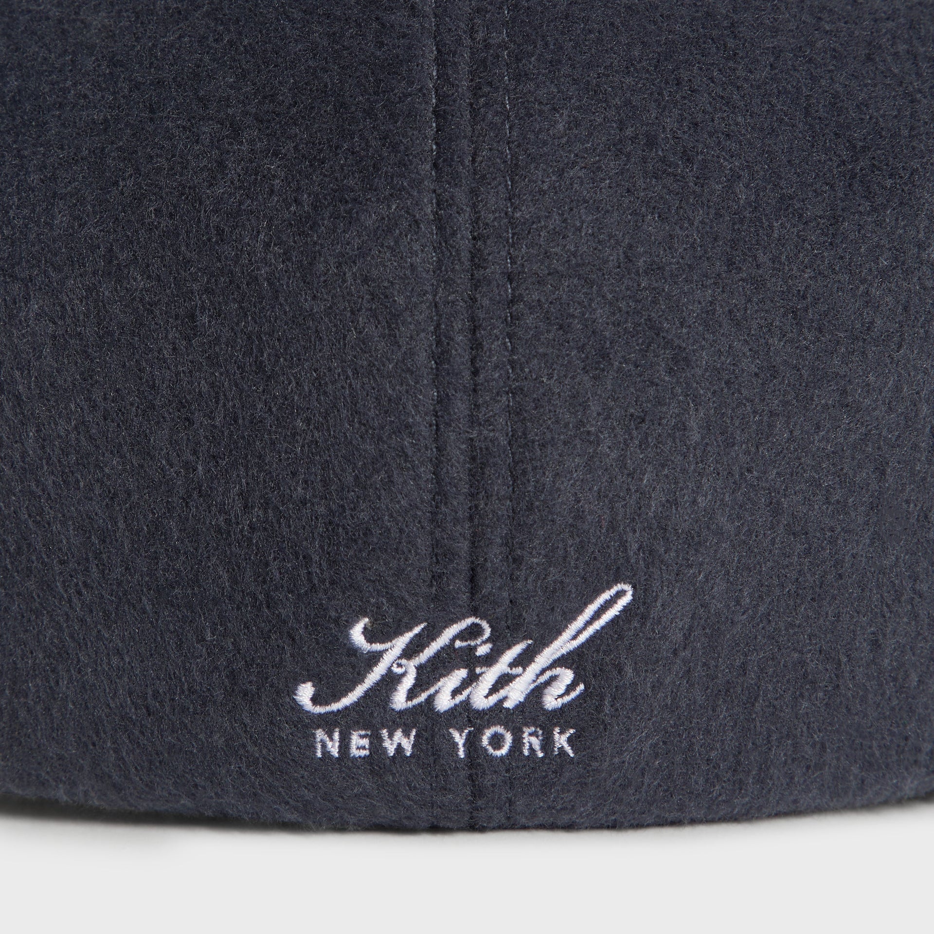 Close-up of the Kith New York script embroidery and brushed wool texture on the Kith Drivers Cap in Nocturnal charcoal.