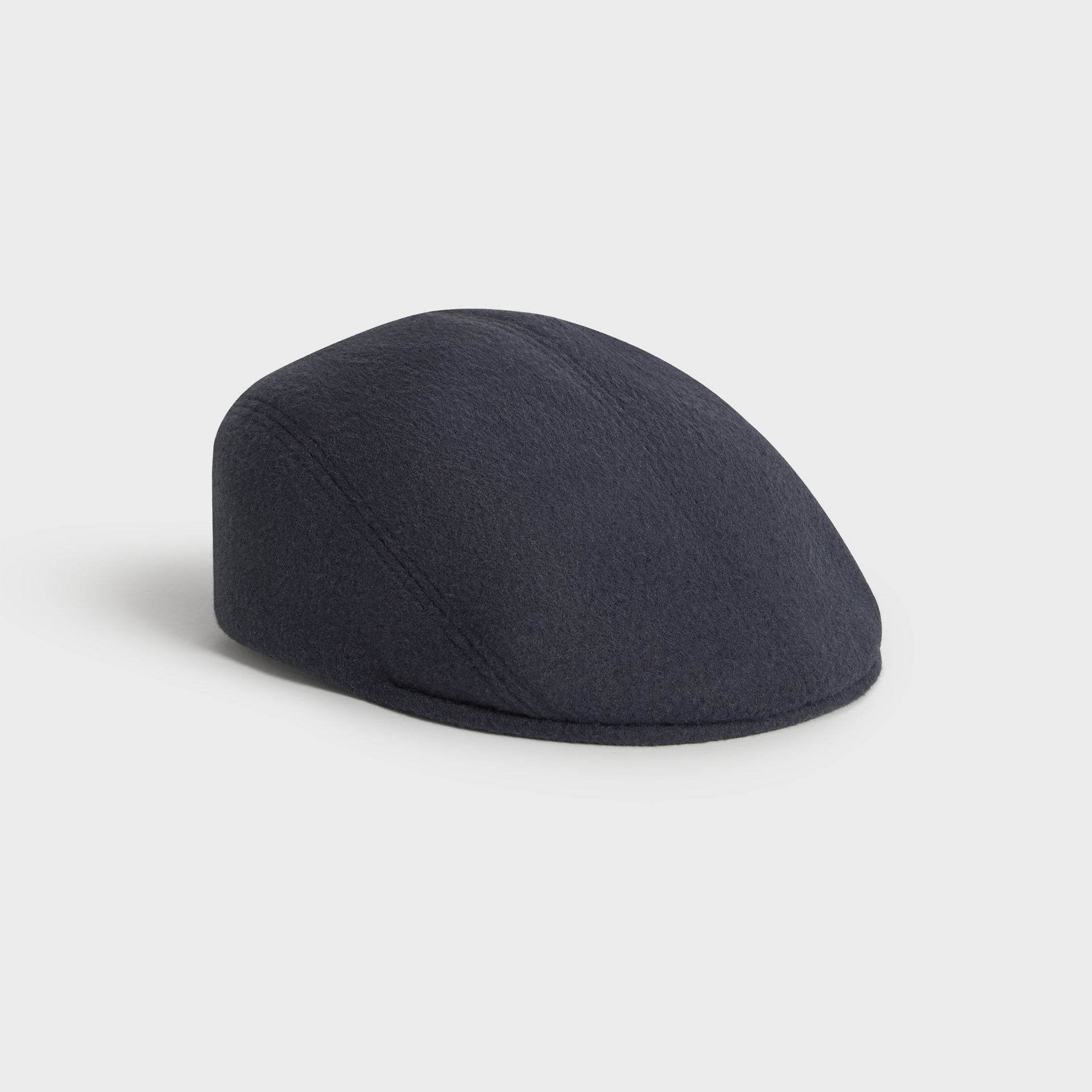 Kith Script Double-Face Wool Drivers Cap in Nocturnal charcoal, three-quarter front view showing the rounded silhouette.