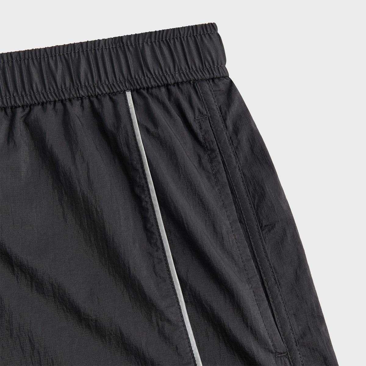 Close-up of Kith Jordan 5-inch Tech Short zip pocket with white piping and reflective trim