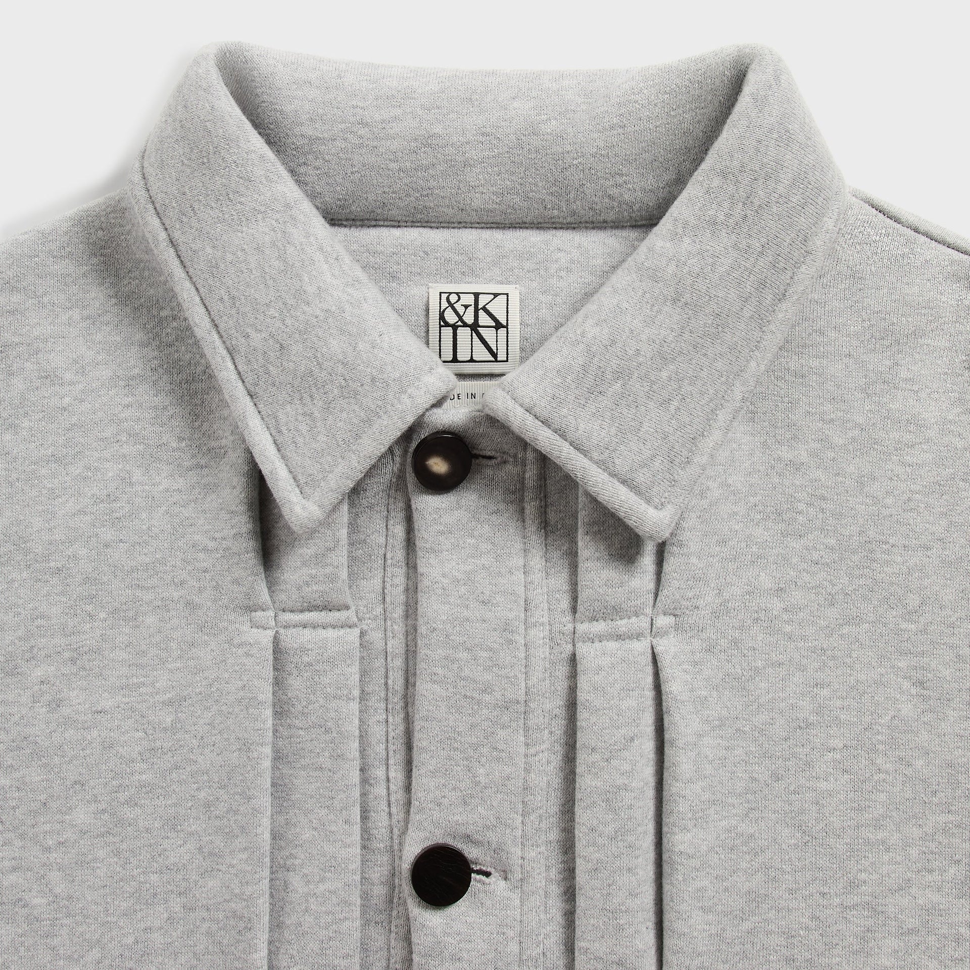 &Kin Eito Jacket detail: spread collar, &Kin woven label and black snap buttons on pleated placket