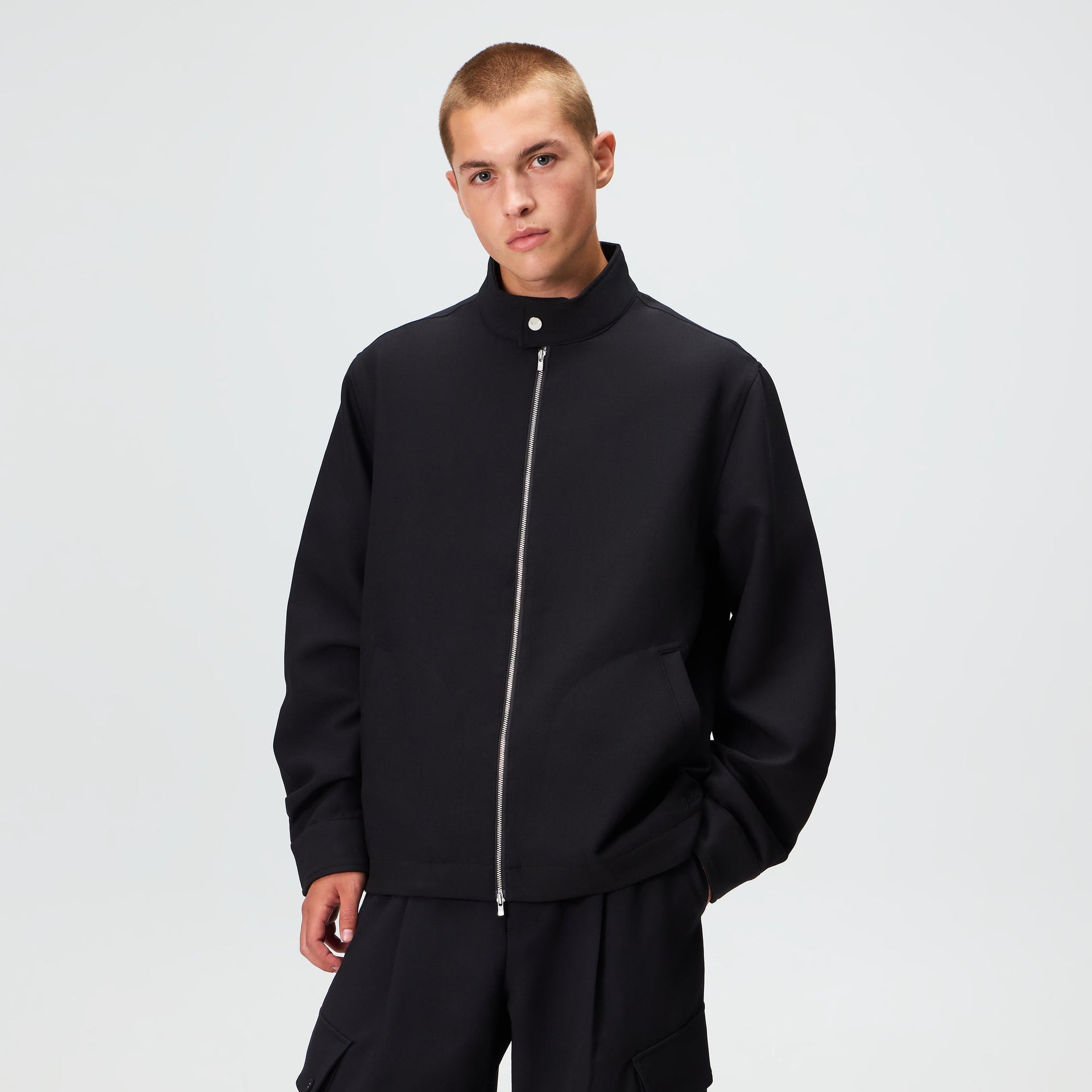 Man wearing the Kith Double Weave Garrison jacket in black with matching trousers