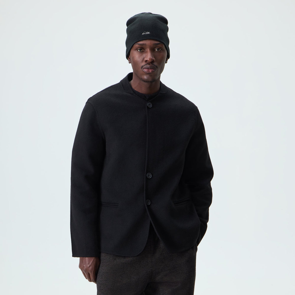 Man wearing black Kith Double-Face Wool Wes jacket with a beanie, front view