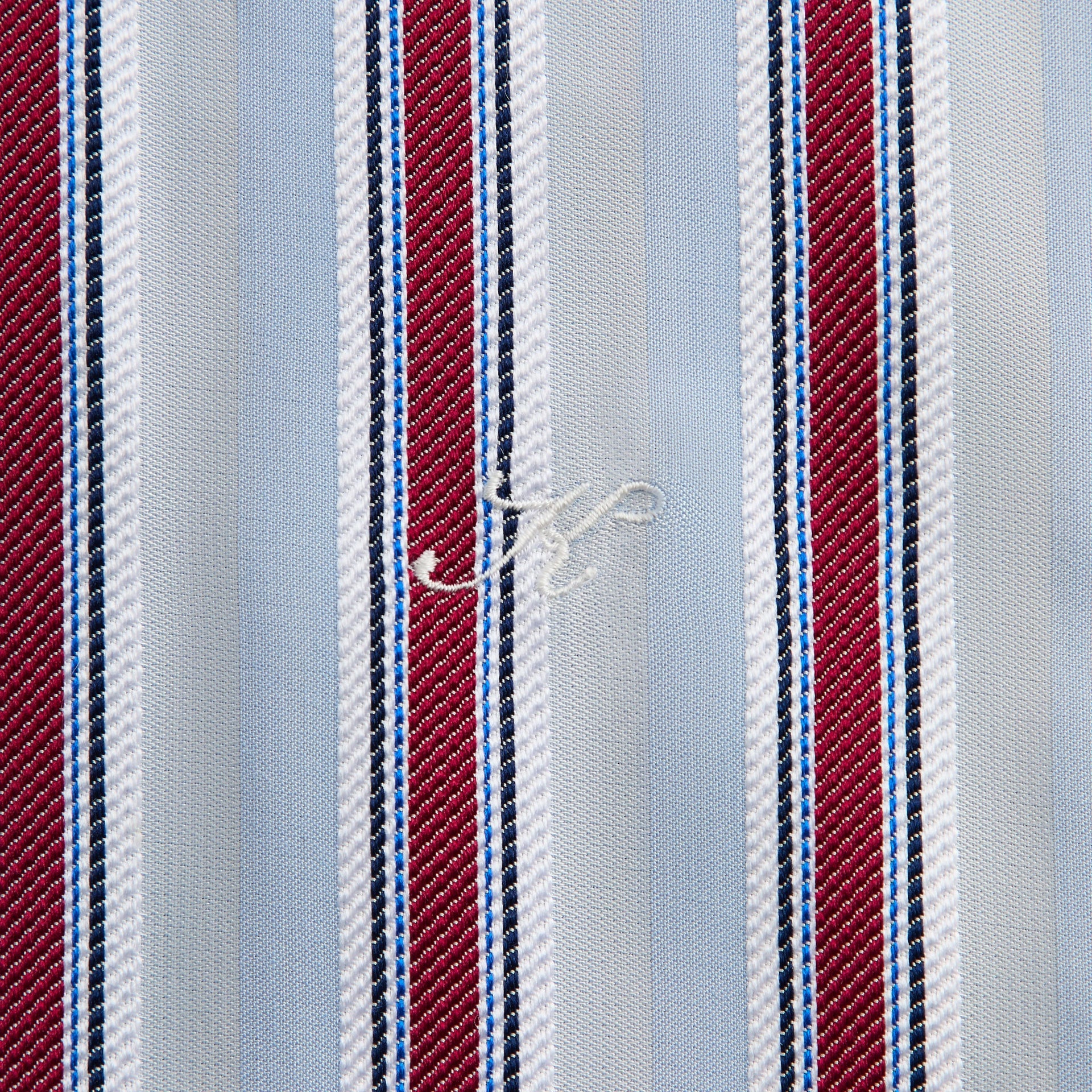 Close-up of the embroidered logo on the striped jacquard fabric of the Kith Thompson shirt