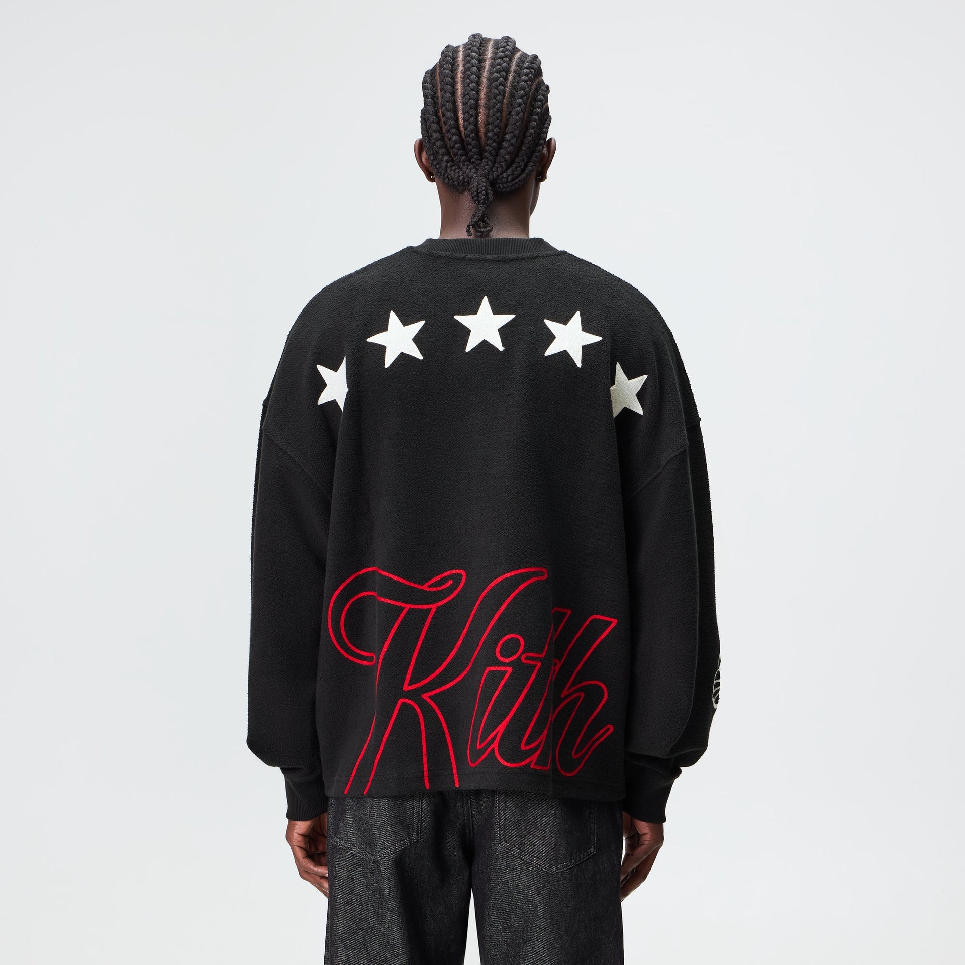 Man wearing the Kith Varsity Lawson crewneck in black, back view showing star and Kith script graphics