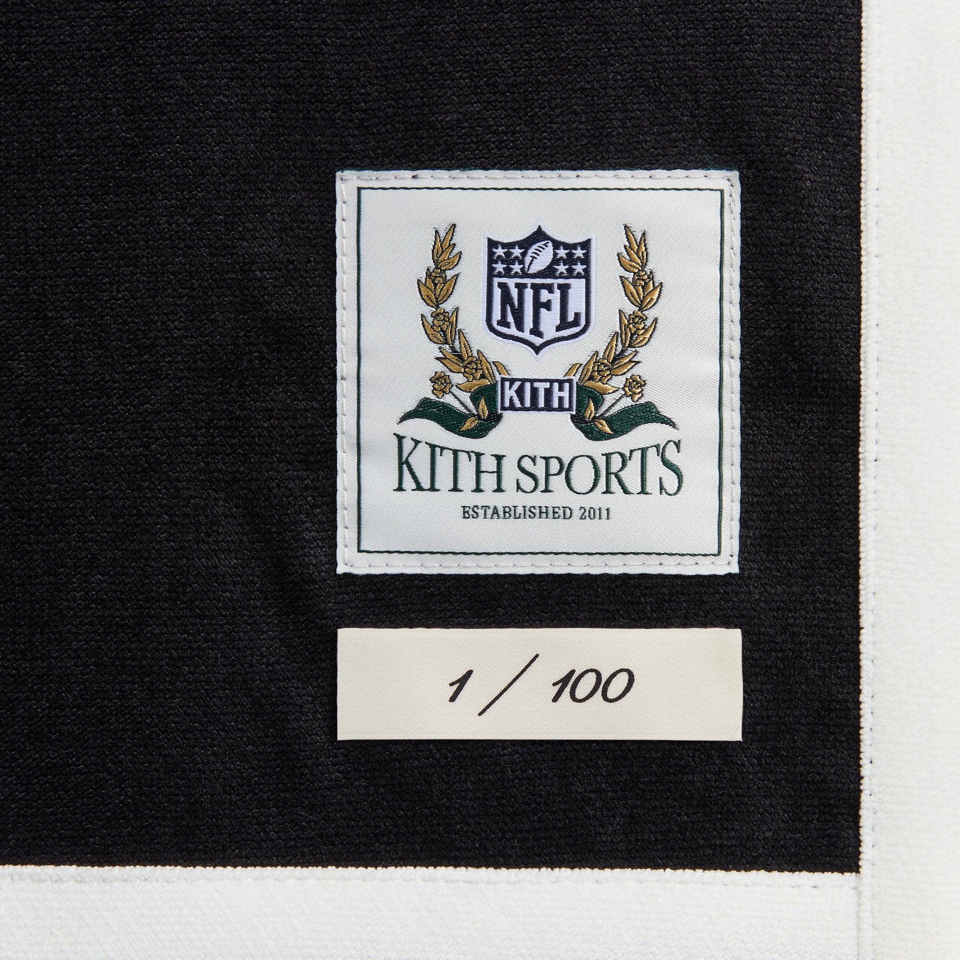 Close-up of the Kith Sports NFL woven label and 1 of 100 numbering tag on the Raiders Leon shirt