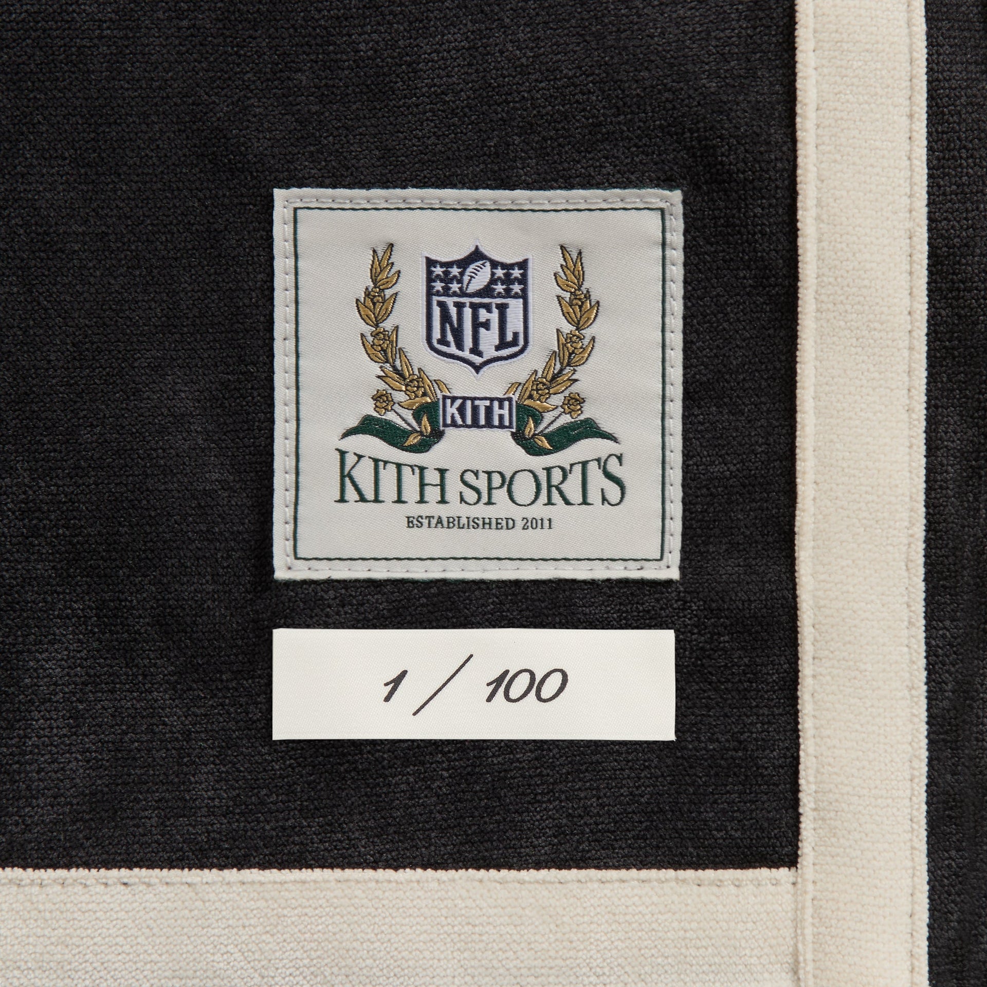 Close-up of the Kith Sports NFL woven label and 1 of 100 numbering tag on the Saints Leon shirt