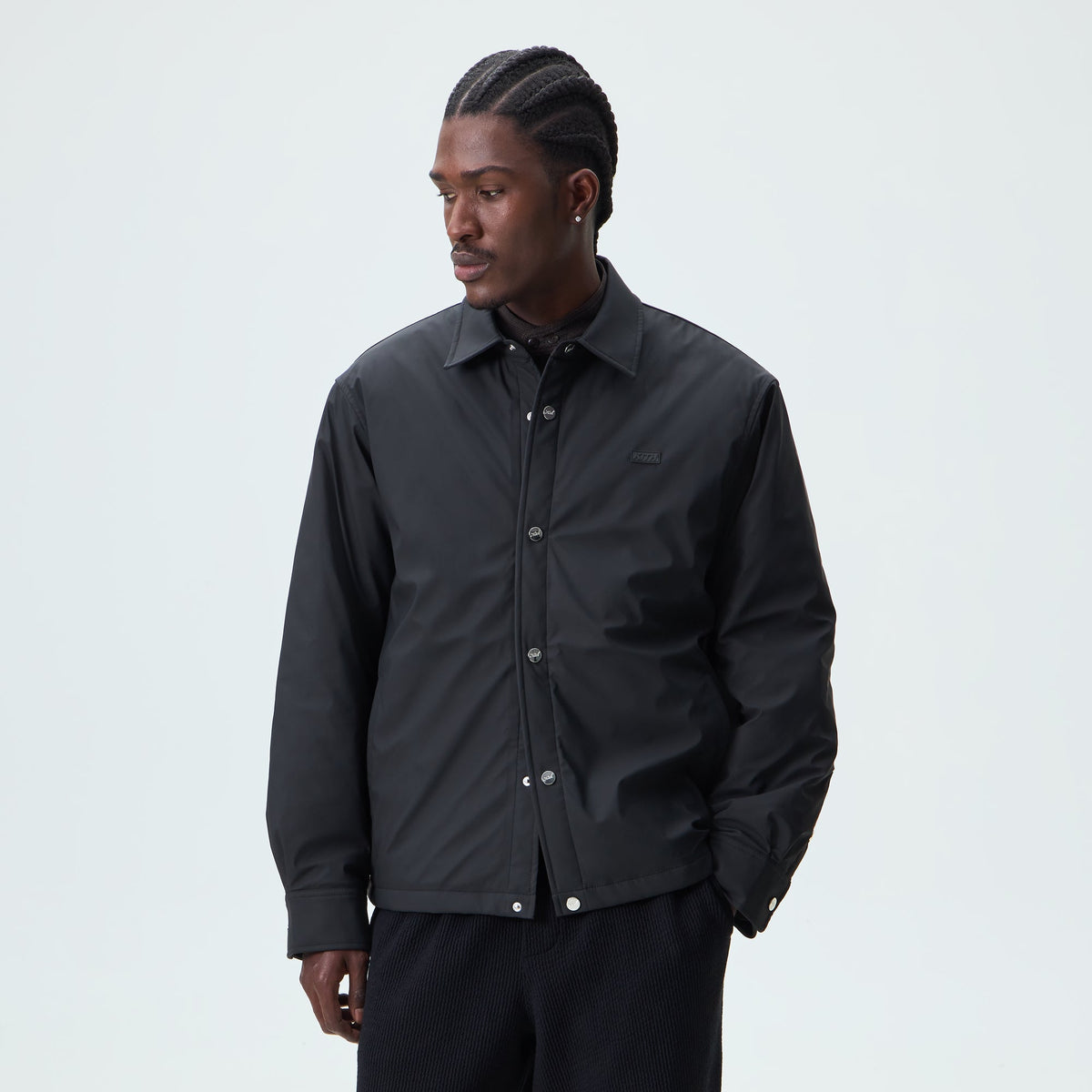 Man wearing black Kith Stretch Poly Brixton shirt jacket, front view