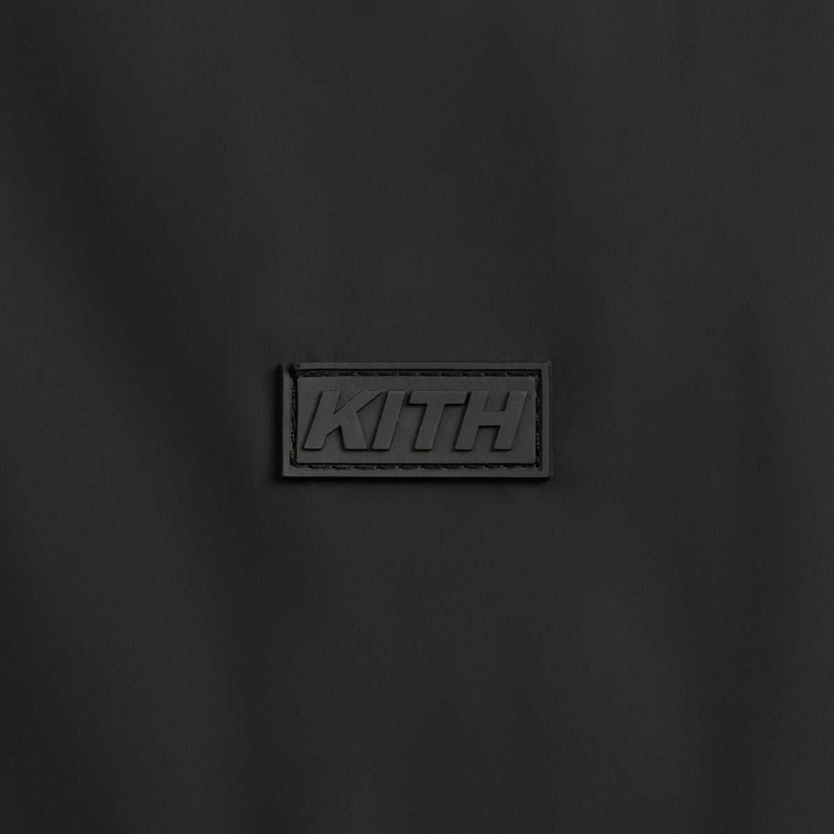 Close-up of the tonal rubber KITH patch on the black Brixton shirt jacket