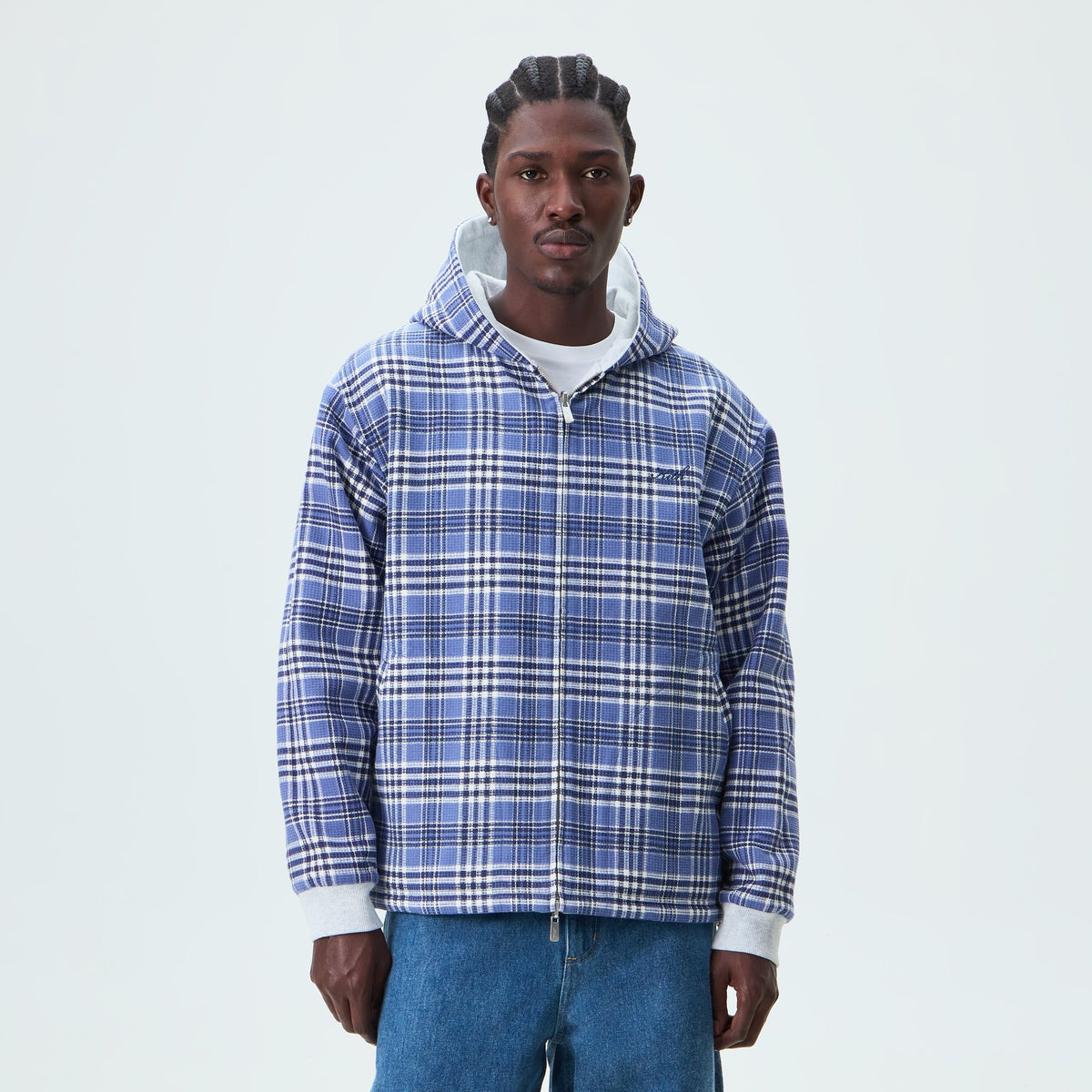 Man wearing the blue plaid side of the reversible Kith Khenny zip-up hoodie, front view