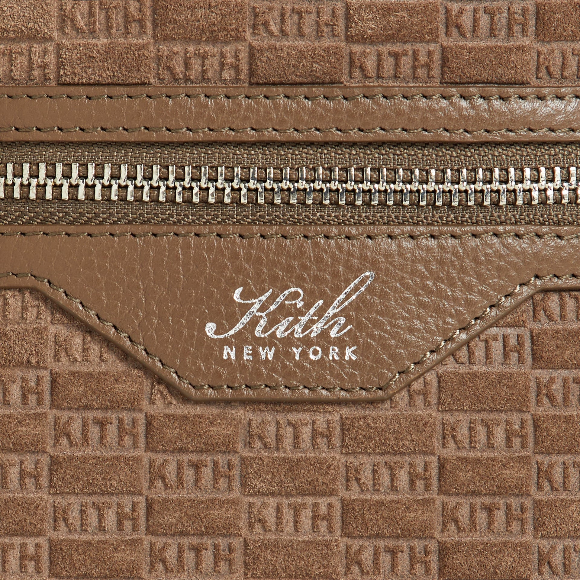 Close-up of the zipper pocket and Kith New York leather logo patch on the Monogram Suede Drawstring Pouch