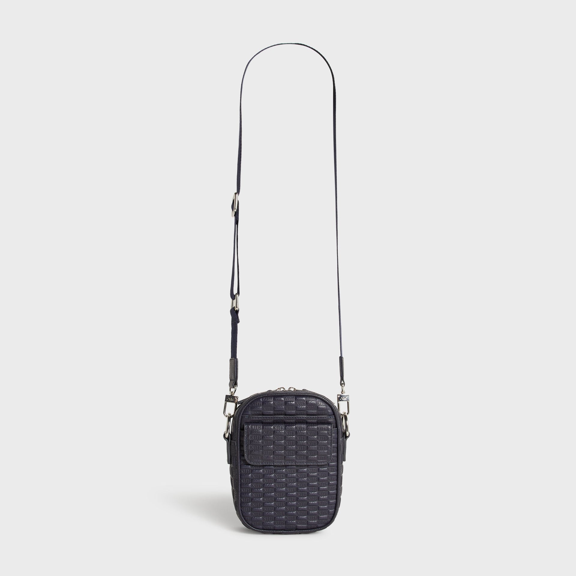Kith Monogram Tumbled Leather Passenger K15 Bag in Ink shown hanging by its full-length crossbody strap