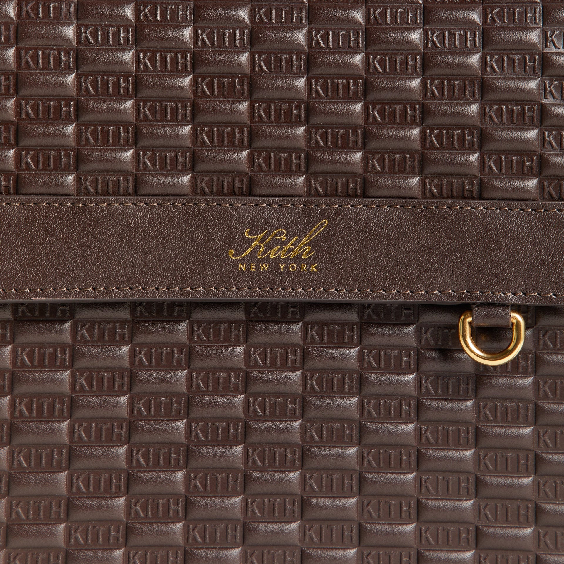 Macro detail of the Kith Monogram Smooth Leather Explorer Pack's embossed KITH logo leather texture and gold foil-stamped Kith New York brand patch