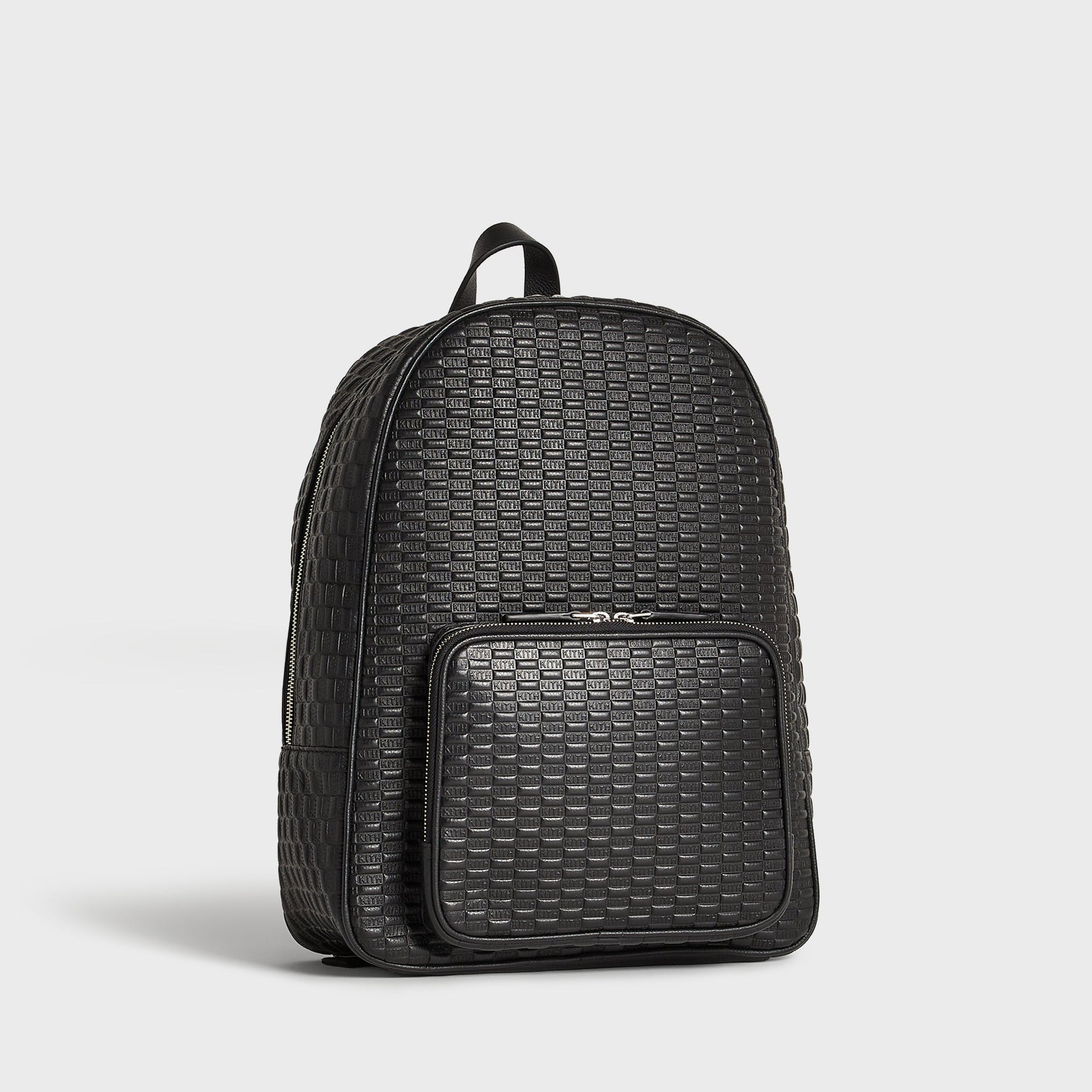 Kith Monogram Tumbled Leather Backpack in black, three-quarter angle view highlighting the embossed KITH pattern and front pocket.