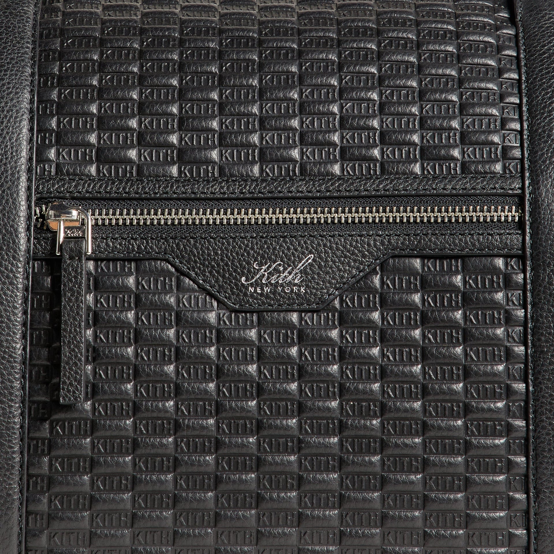 Close-up detail of the Kith Monogram Tumbled Leather Traveler K55 Duffle Bag's front zip pocket with embossed Kith New York wordmark.