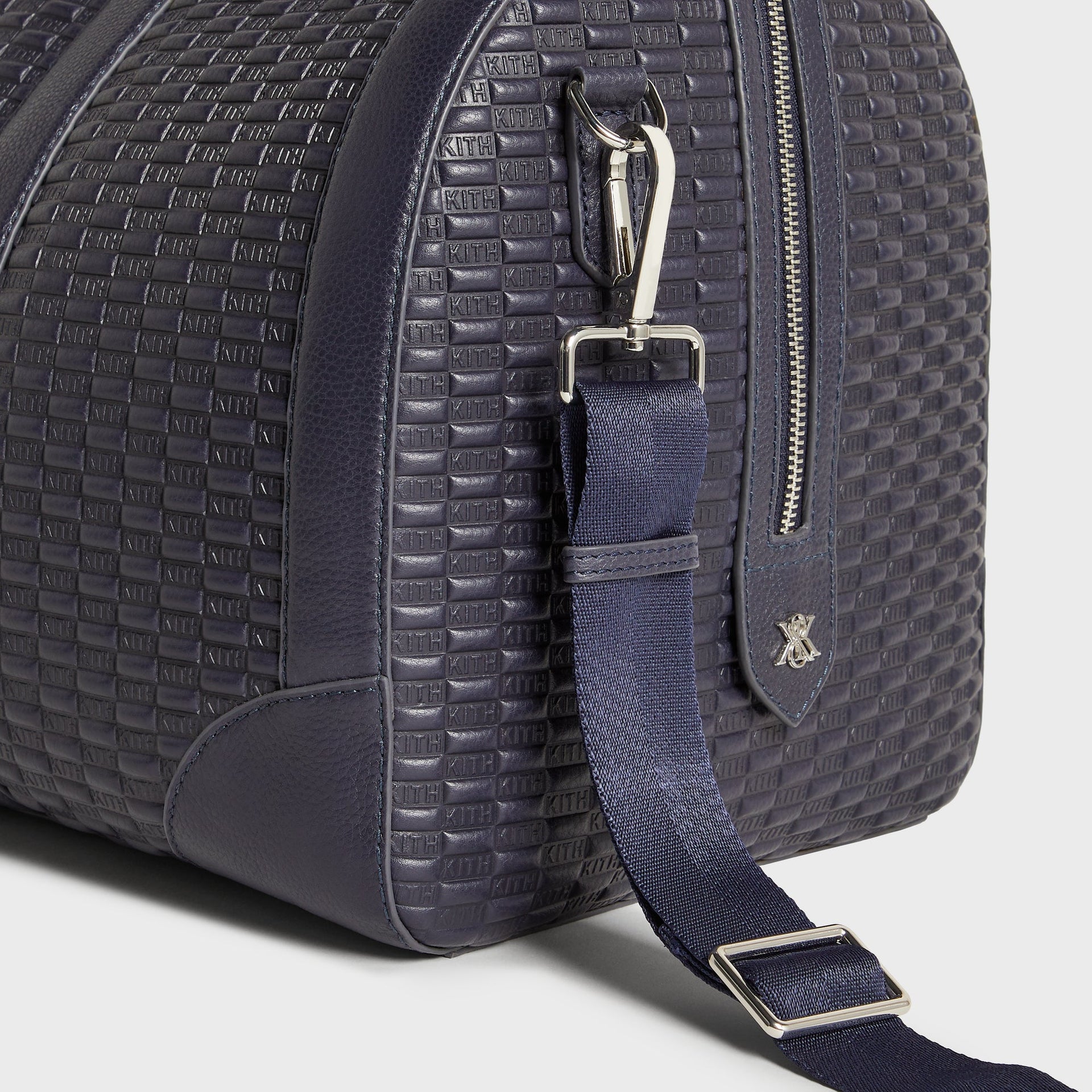 Close-up detail of side handle clip, zipper hardware and Kith logo tab on Traveler Duffle Bag in Ink