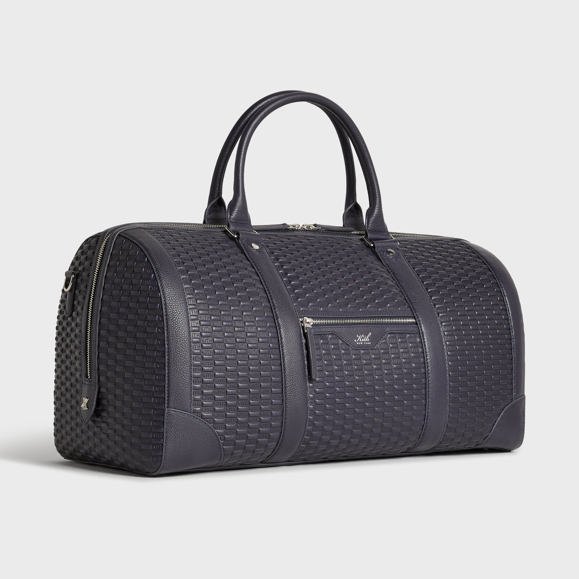 Kith Monogram Traveler K55 Duffle Bag in Ink, angled 3/4 view showing front zip pocket and crossbody strap