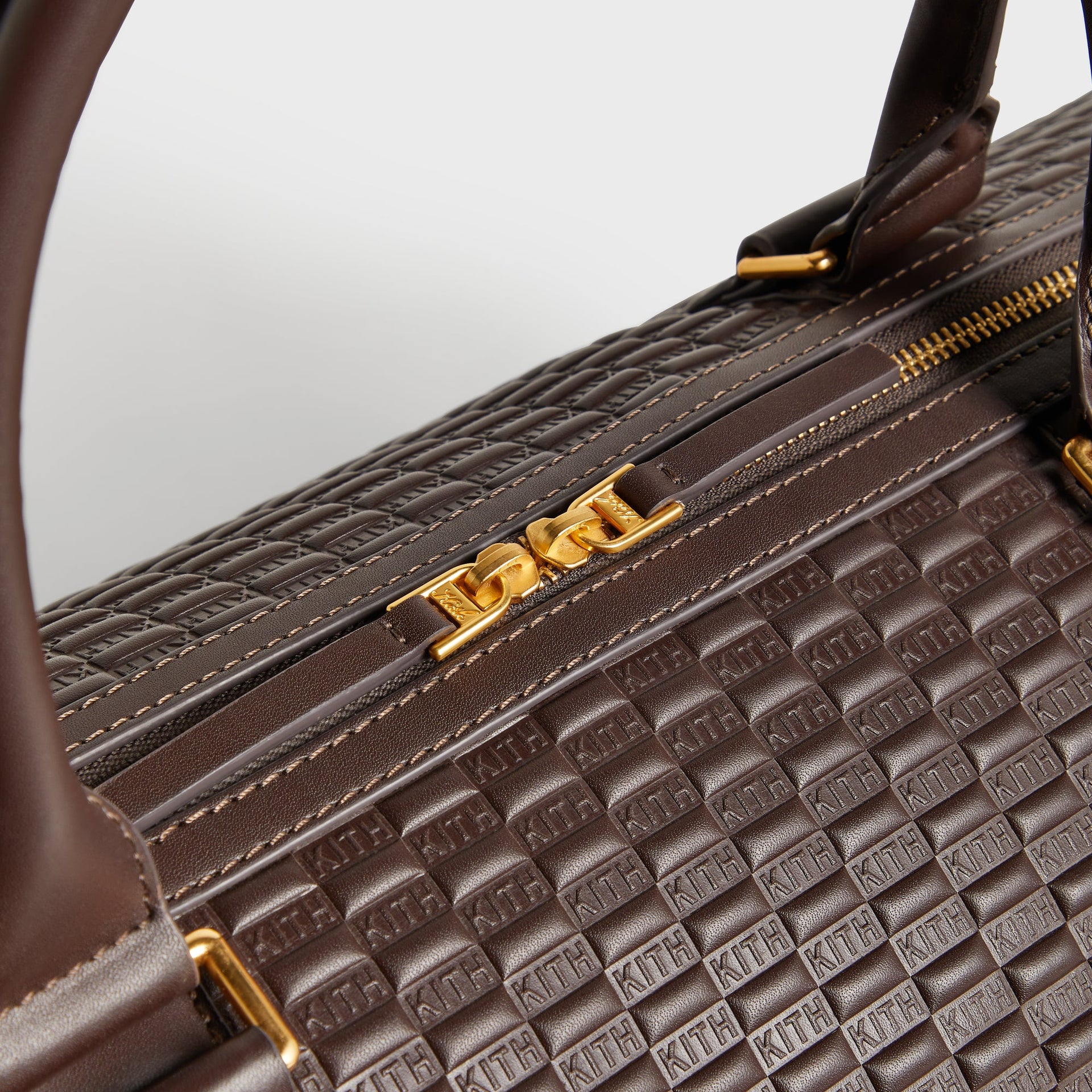 Close-up of top handle stitching and gold zipper pull on the Kith Traveler K55 Duffle Bag