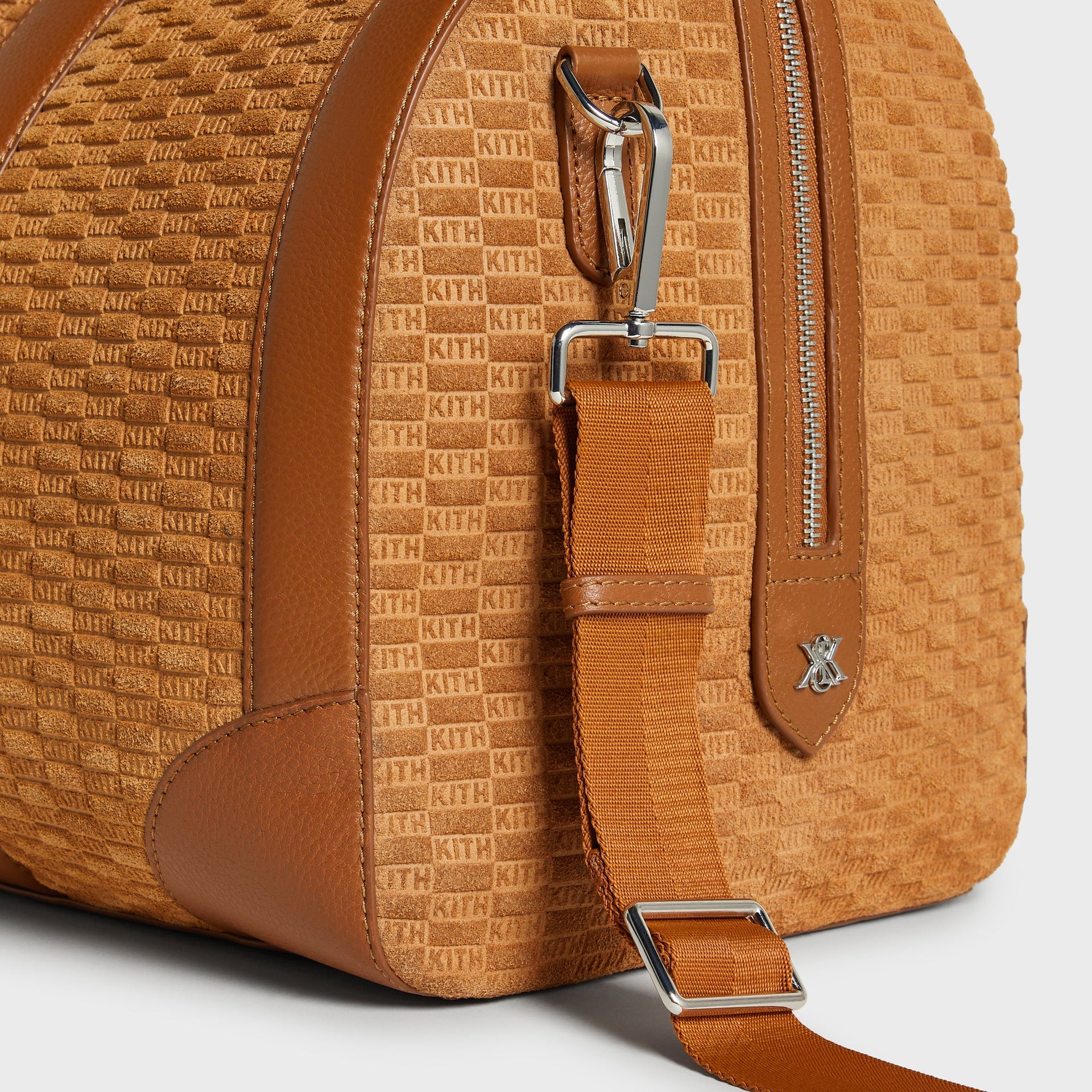 Close-up of side panel showing embossed KITH suede pattern and crossbody strap clip on Traveler K55 Duffle Bag