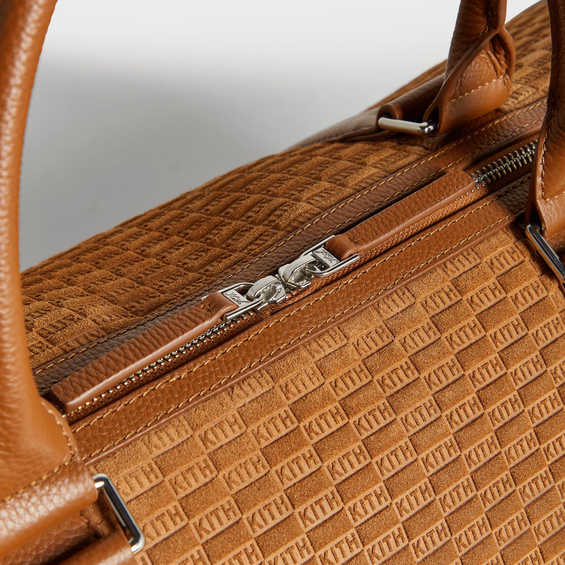 Close-up of leather top handles and zipper pulls on Kith Traveler K55 Duffle Bag in Argil suede