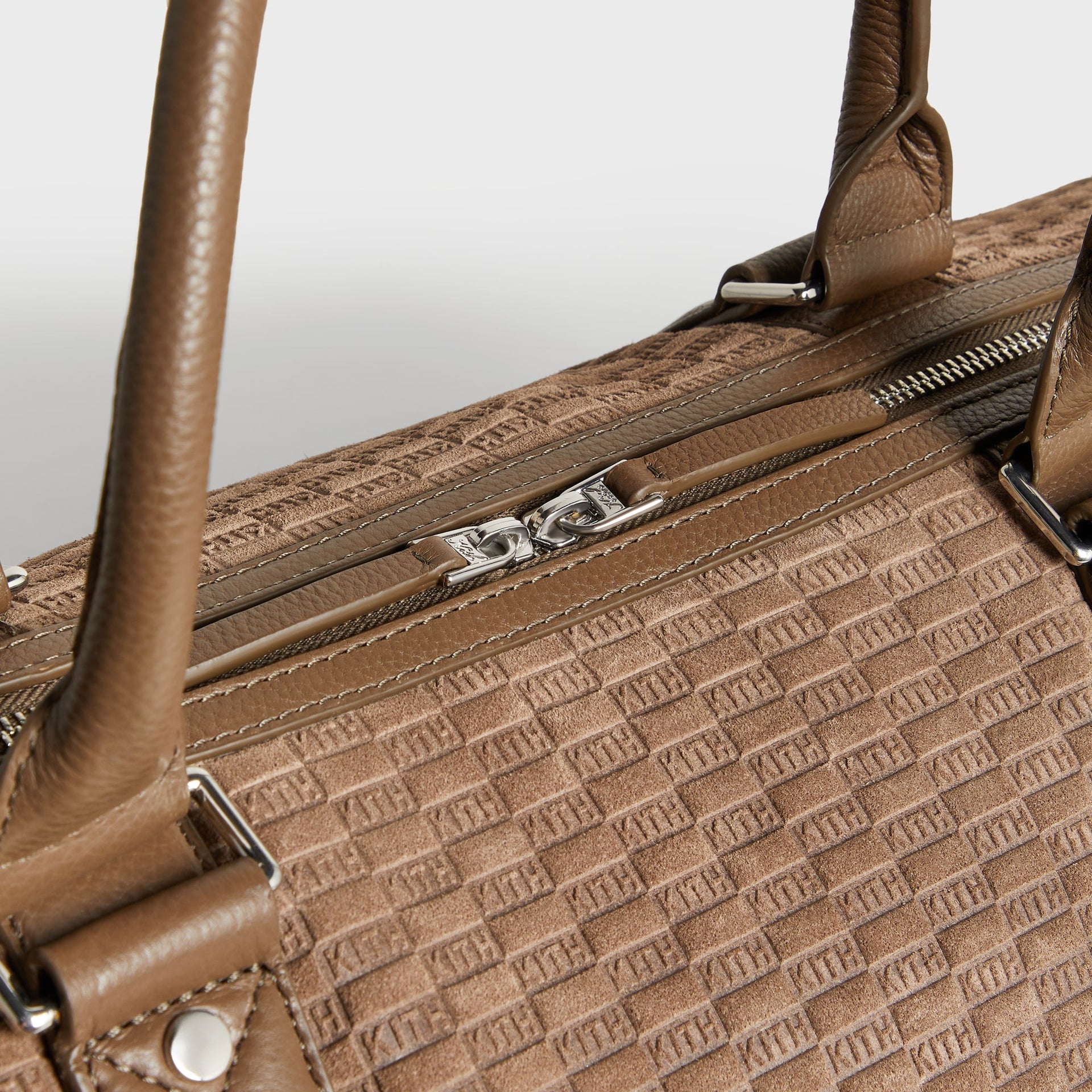 Close-up of top handle stitching and silver zipper pull on the Kith Suede Traveler K55 Duffle Bag