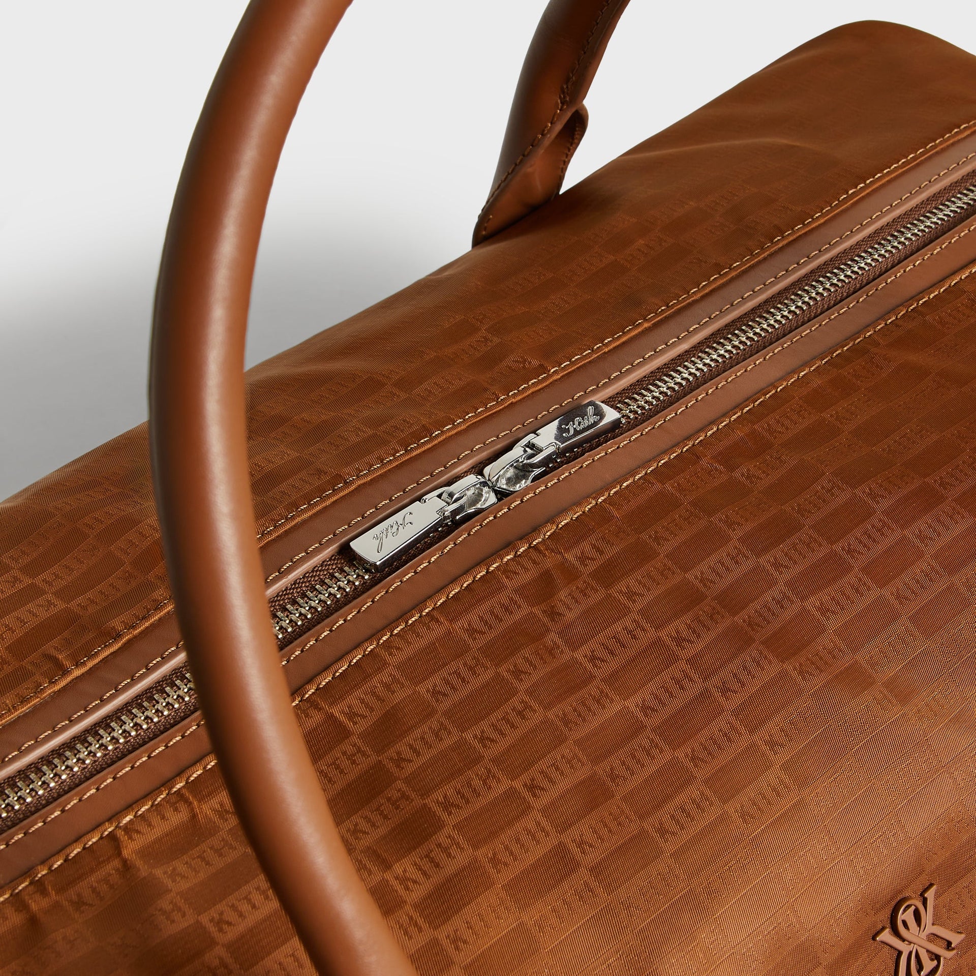 Kith Monogram Nylon Leather Duffle Bag in Tectonic, close-up of zipper pull engraved with Kith script logo