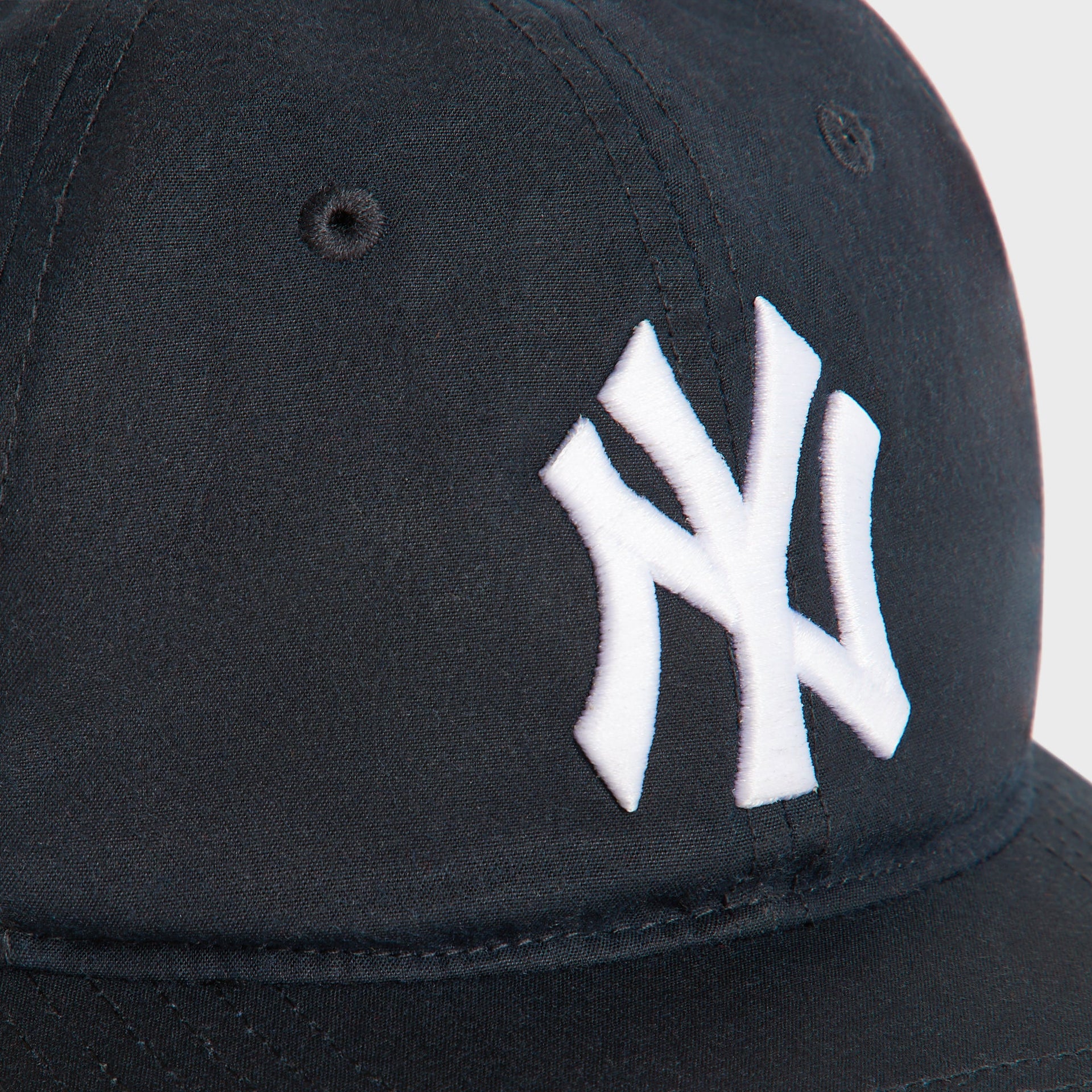 Close-up of the white embroidered NY logo on the navy Nocturnal Kith & '47 Yankees Waxed Cotton cap.