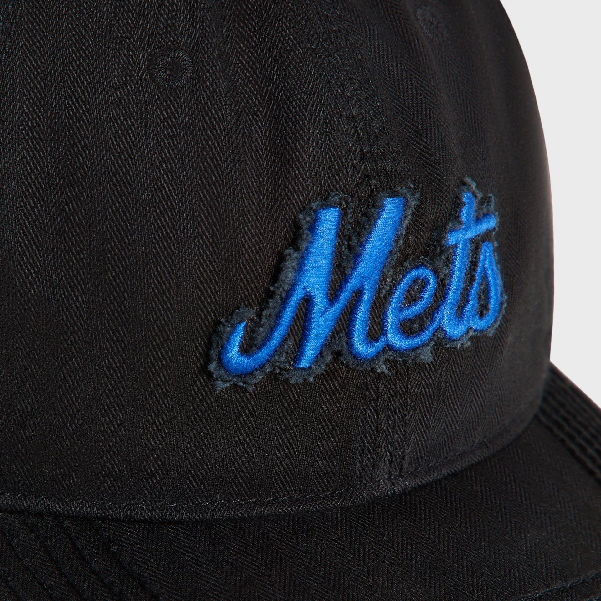 Close-up detail of blue Mets script logo embroidery on black herringbone fabric, Kith & '47 Franchise cap