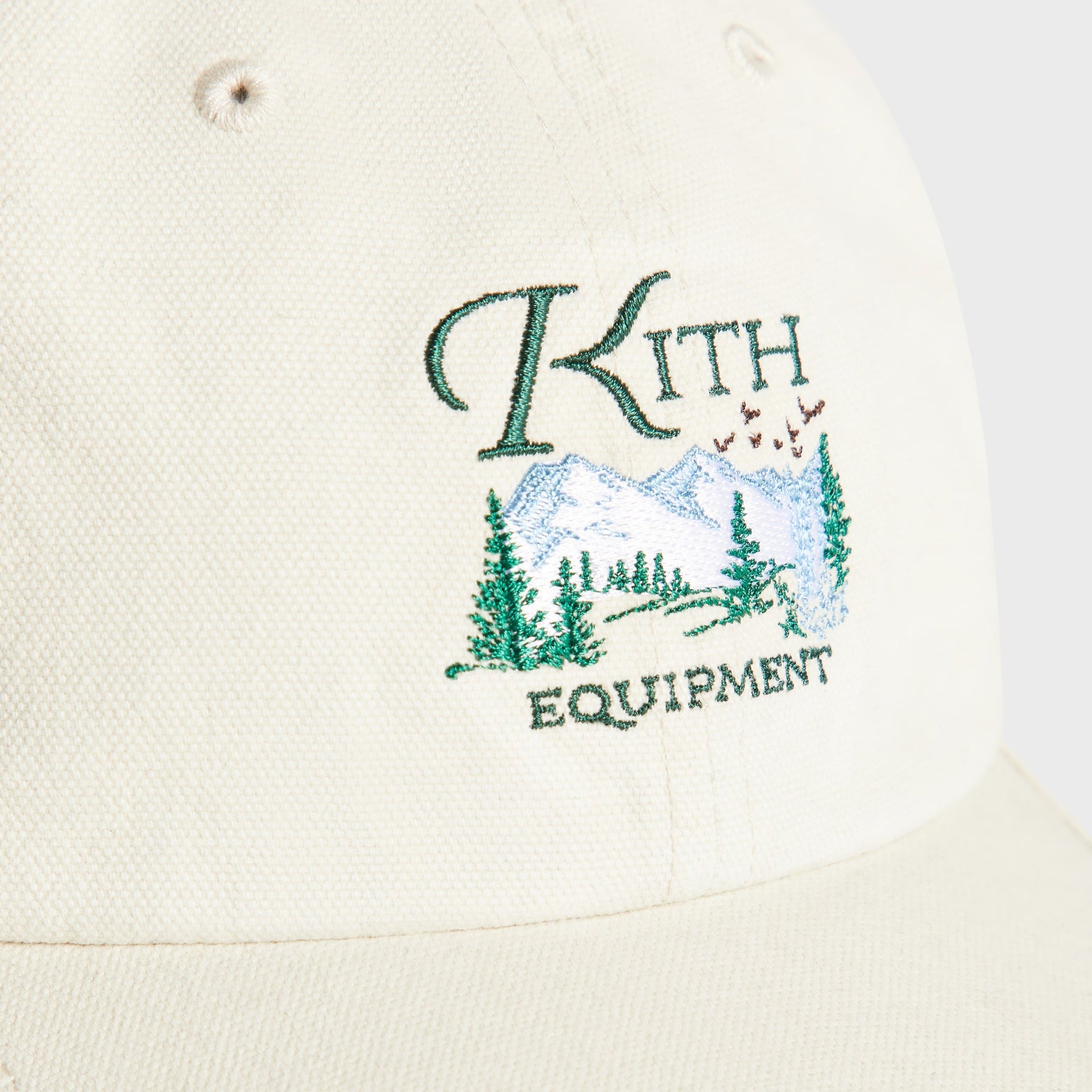 Close-up detail of embroidered Kith Equipment mountain and pine tree logo on Sandrift canvas cap
