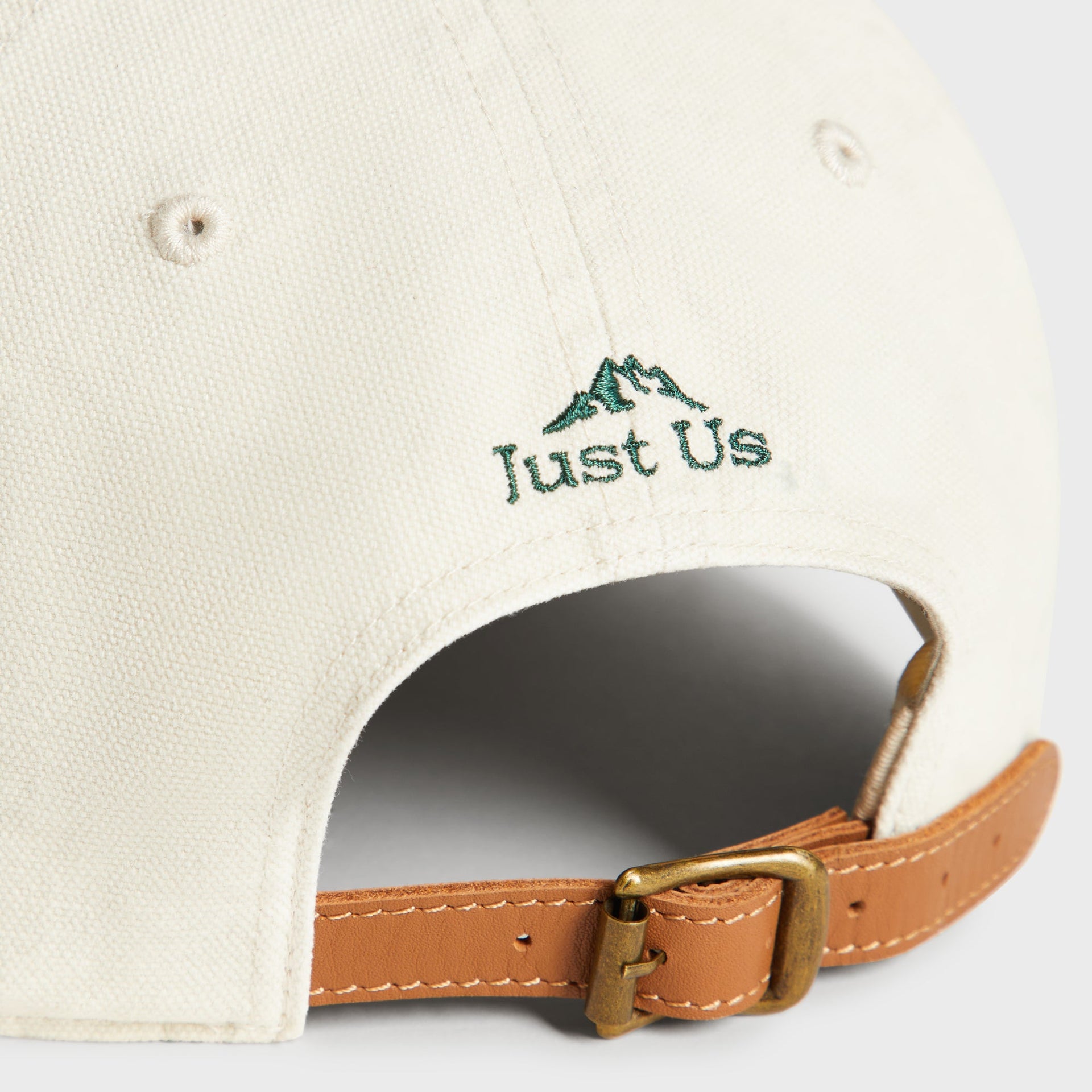 Close-up detail of adjustable brass buckle and leather strap on back of Sandrift canvas cap