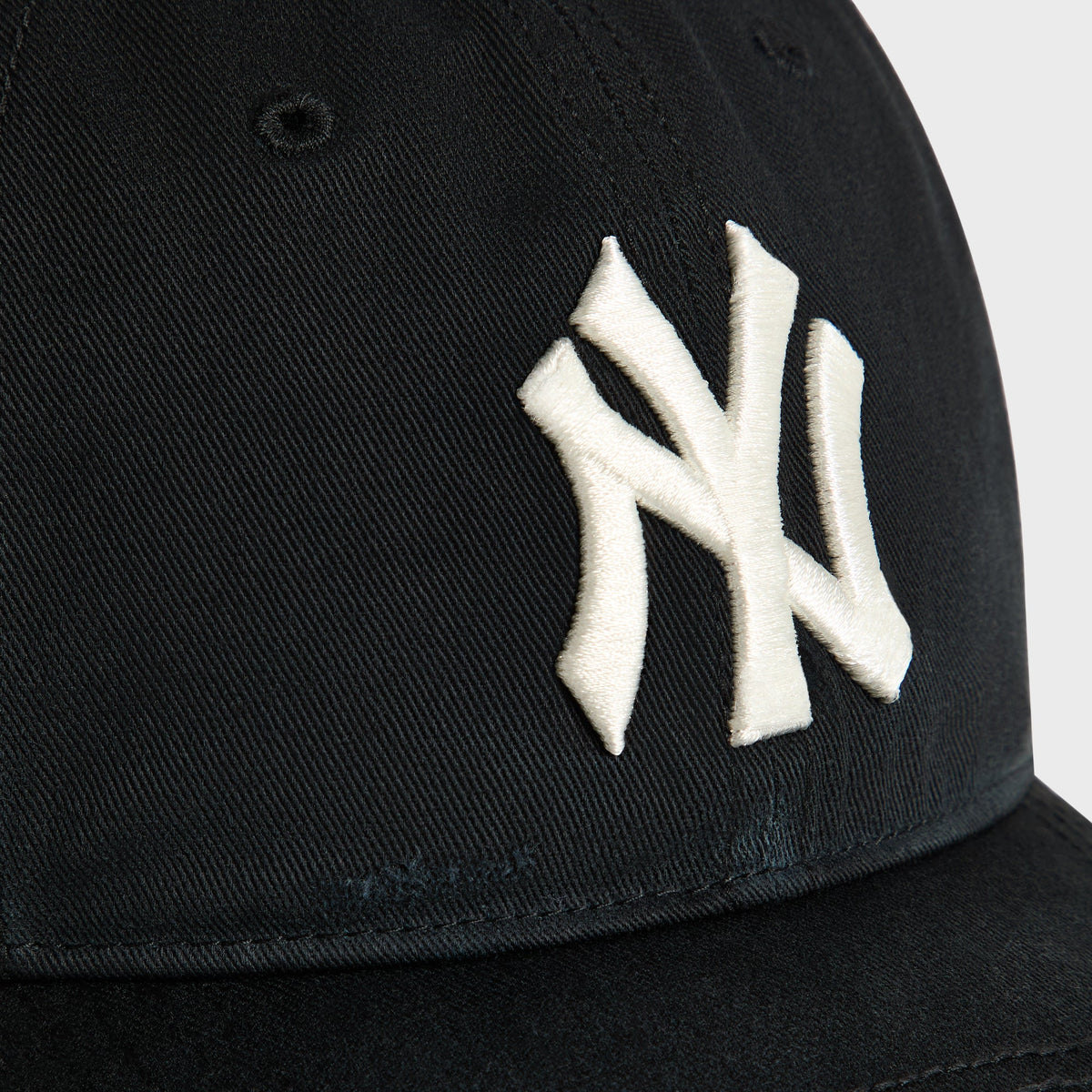Close-up of embroidered white NY logo on Kith & '47 Yankees Sun Faded Franchise cap in black