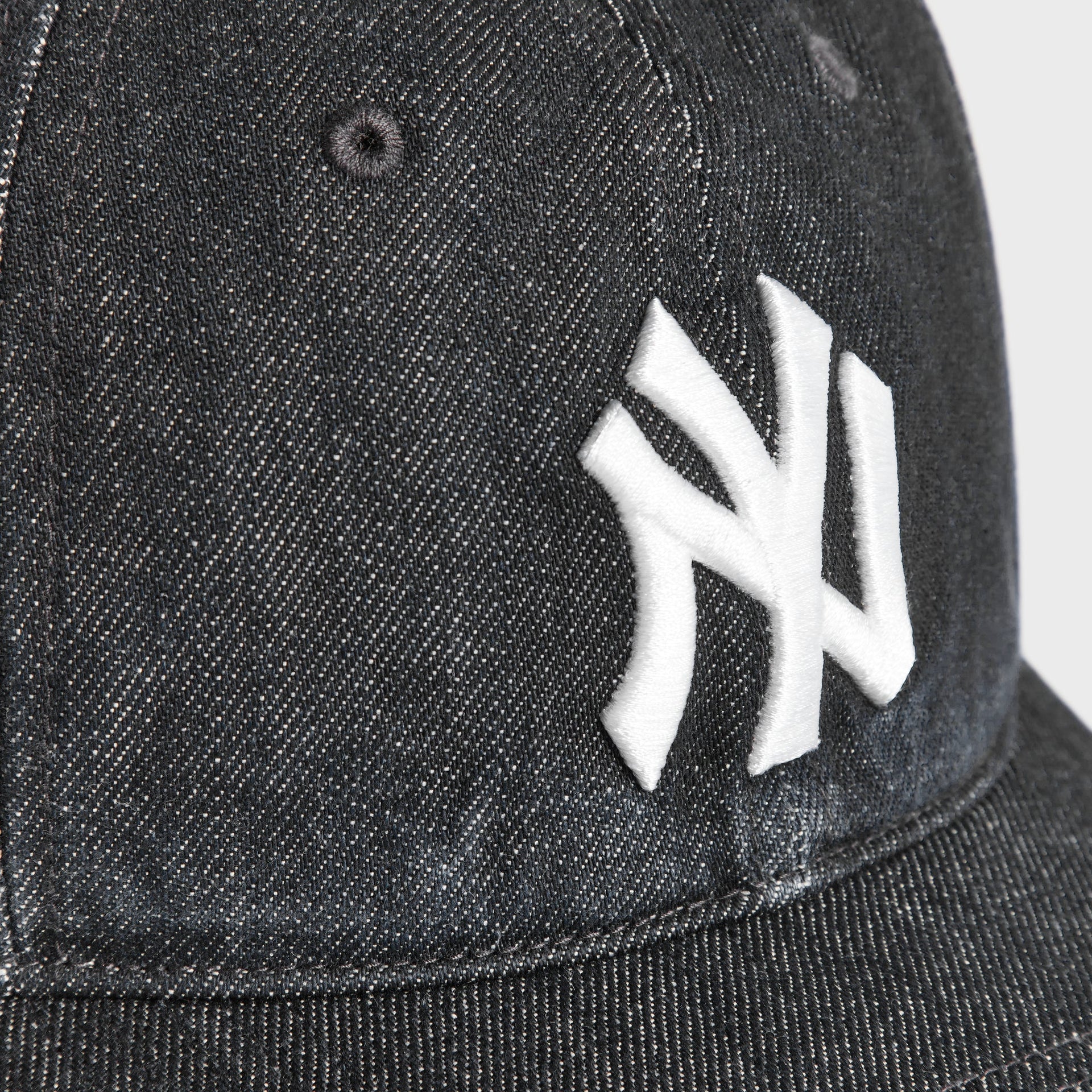 Close-up detail of embroidered white NY Yankees logo on Kith & '47 Denim Franchise cap in Black