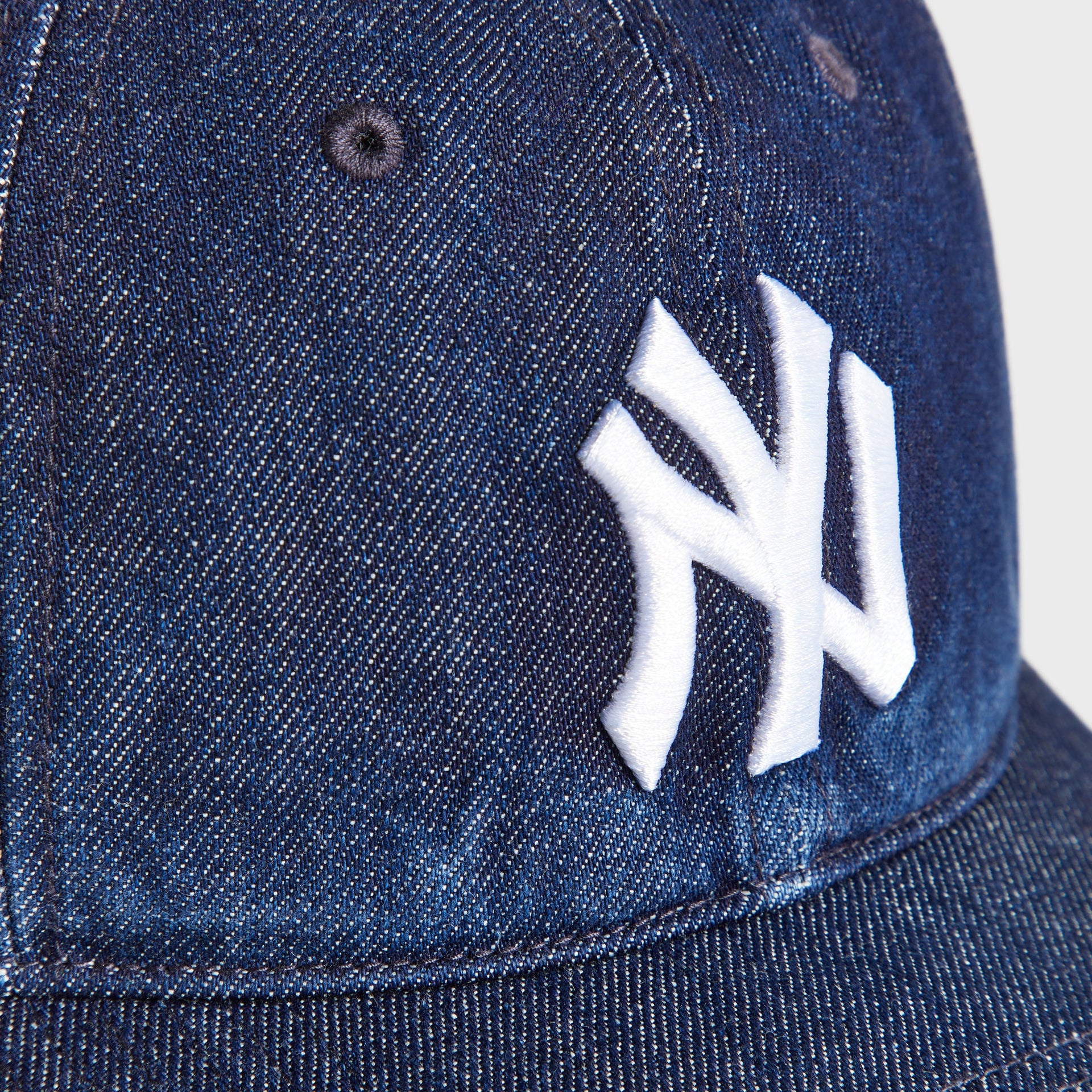 Close-up of the white embroidered New York Yankees NY logo on the Kith & '47 Denim Franchise Cap