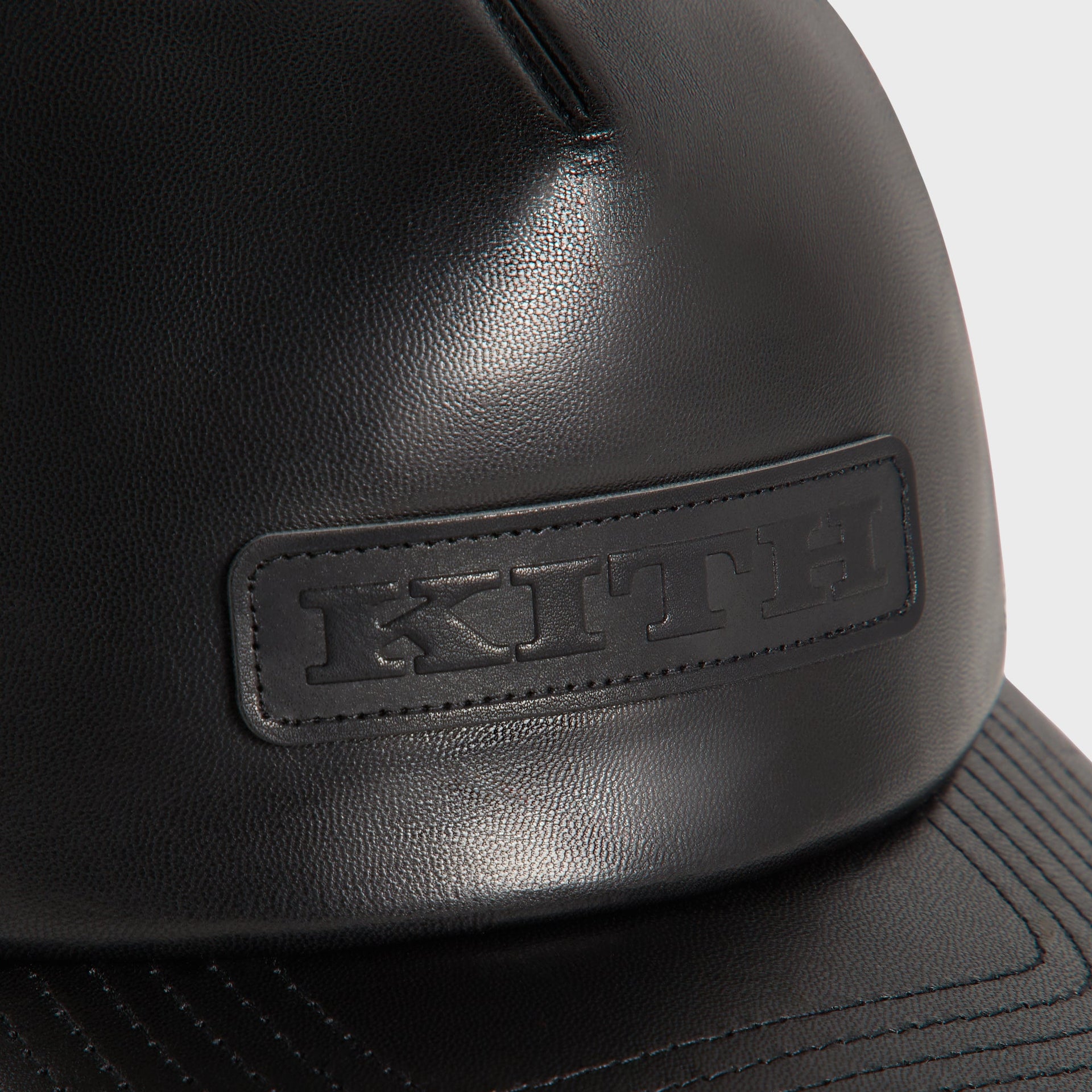 Kith Smooth Leather Nolan Trucker Hat in Black, close-up of embossed KITH leather patch logo