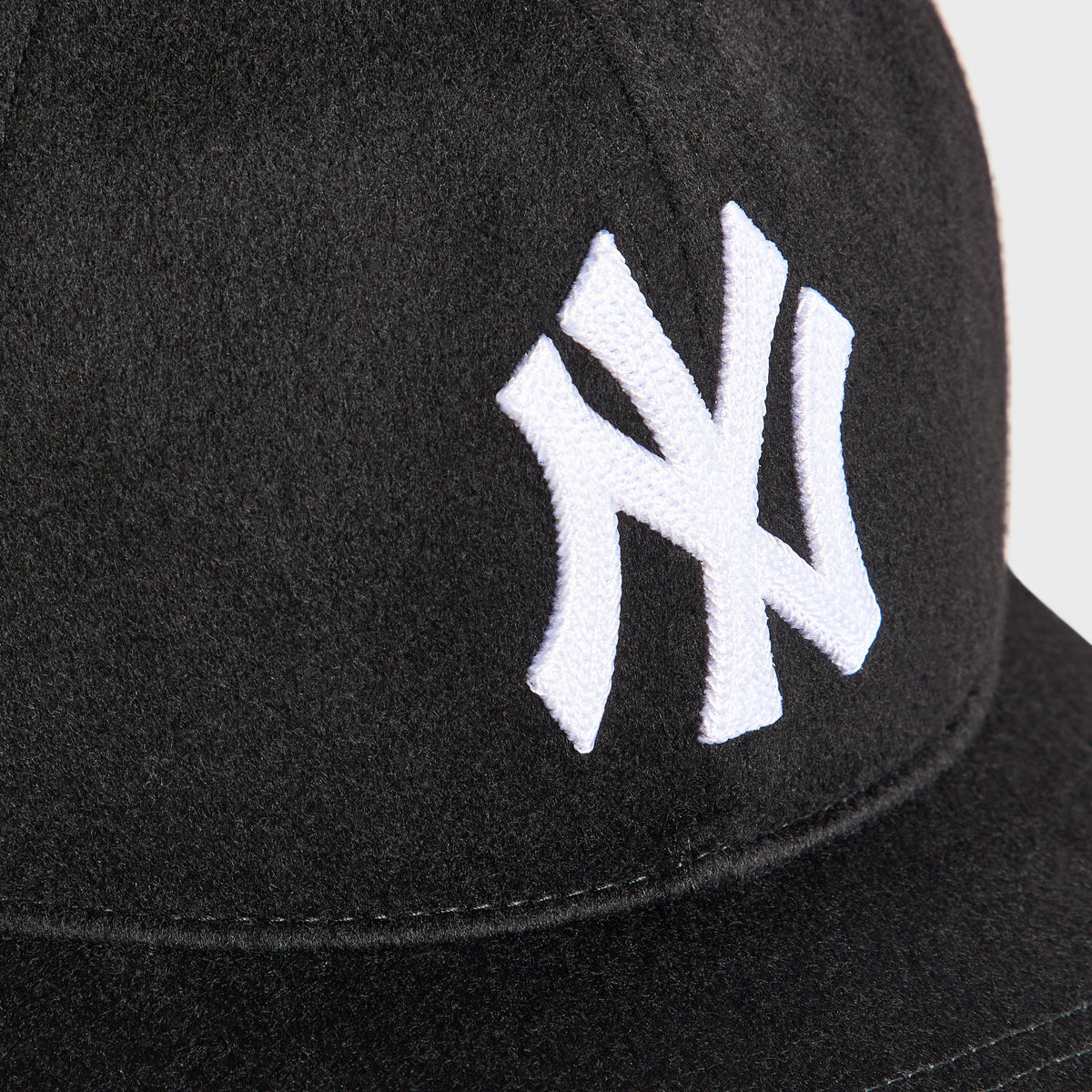 Close-up of white chain-stitched NY logo on the Giorgio Armani & Ronnie Fieg for '47 black wool fitted cap