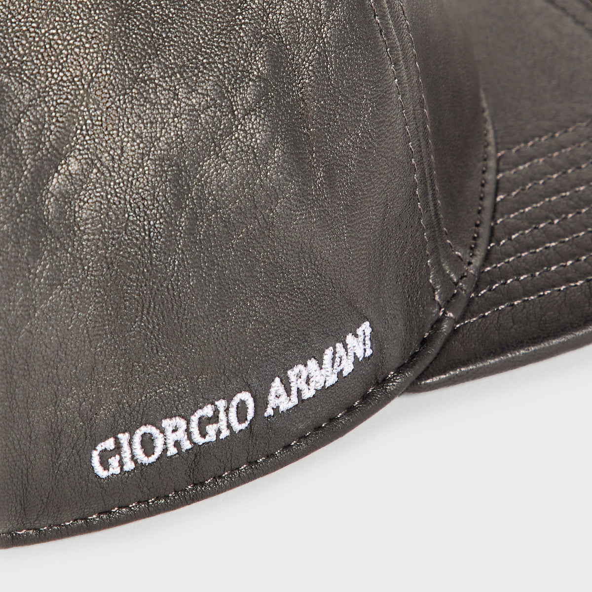 Close-up of white Giorgio Armani embroidery and stitching on the side of the black soft leather Hitch cap